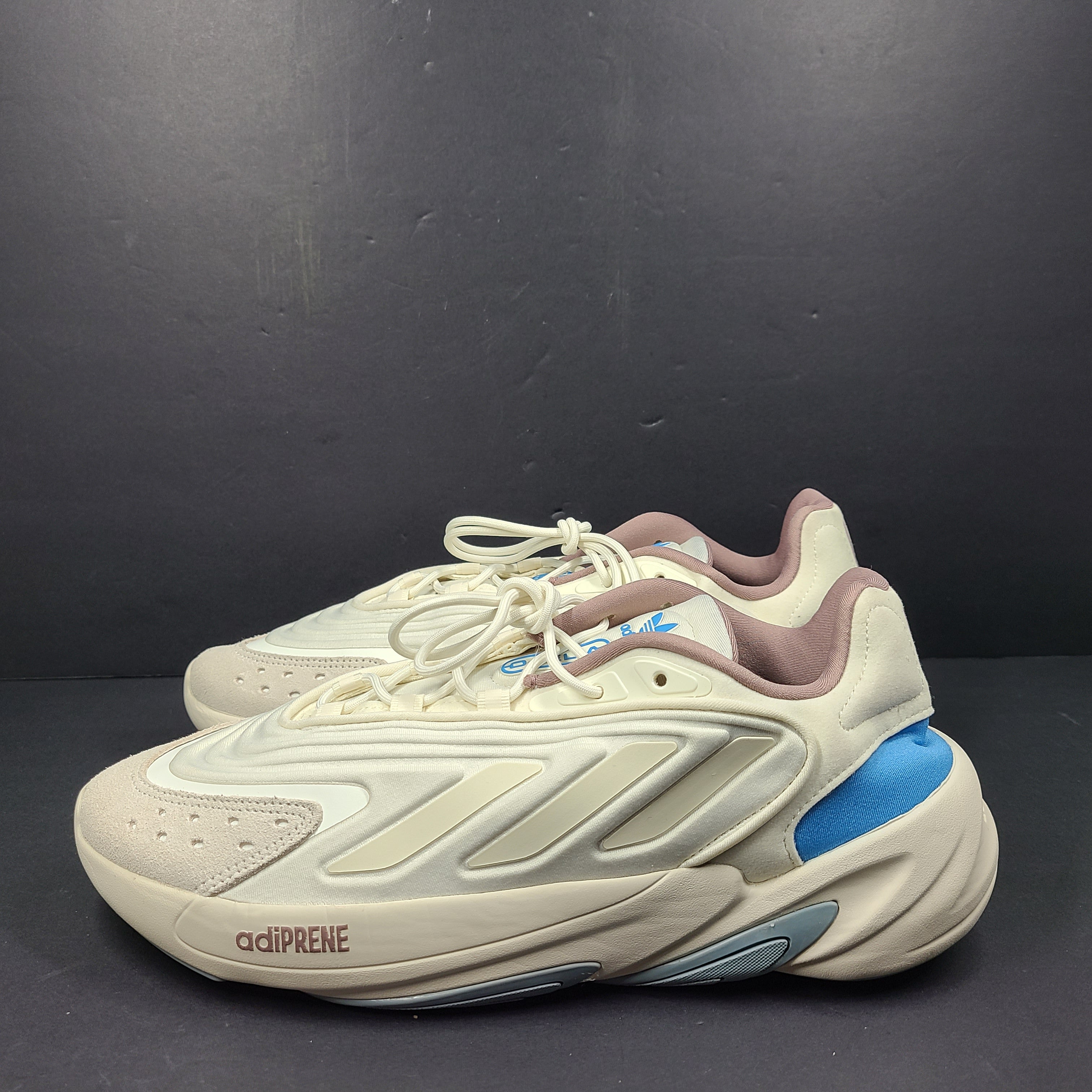 A pair of cream and blue Adidas adiPRENE sneakers in size 9.5 for men.