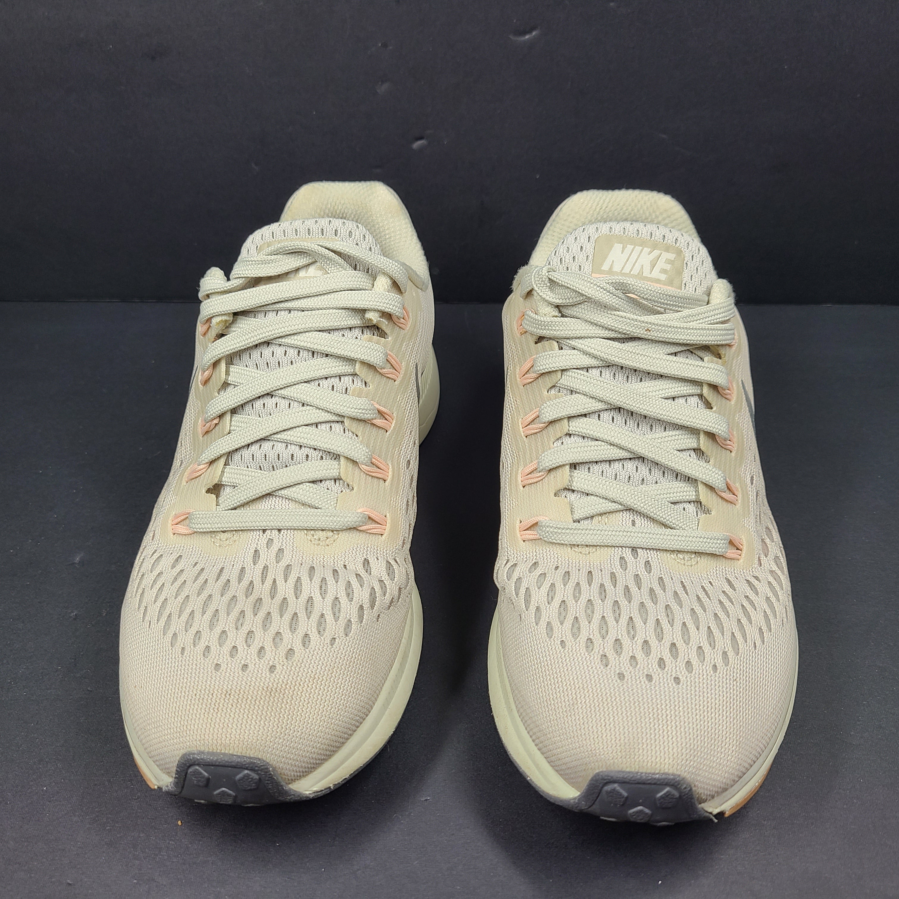 A pair of beige Nike Zoom running shoes.