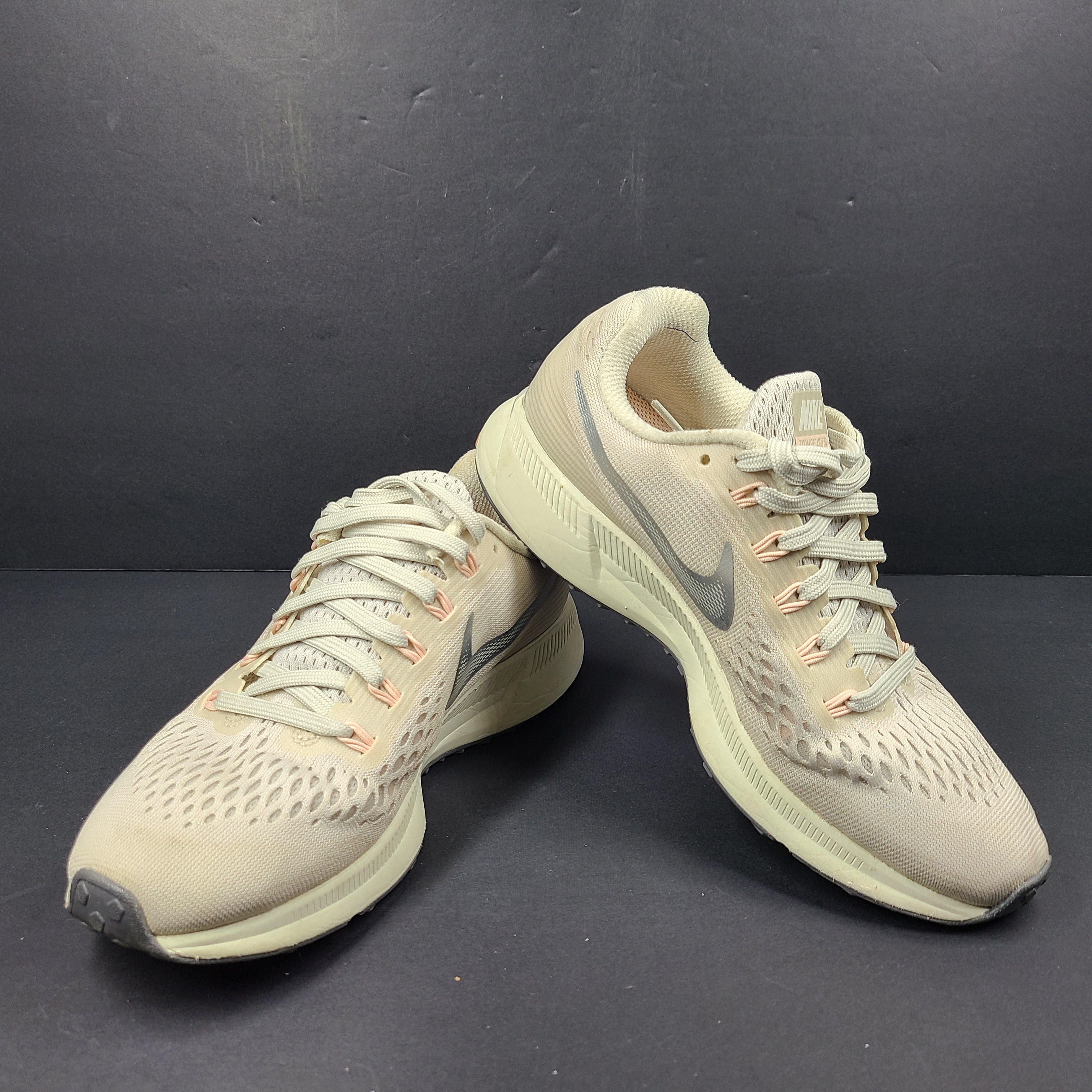 A pair of beige Nike Zoom running shoes.