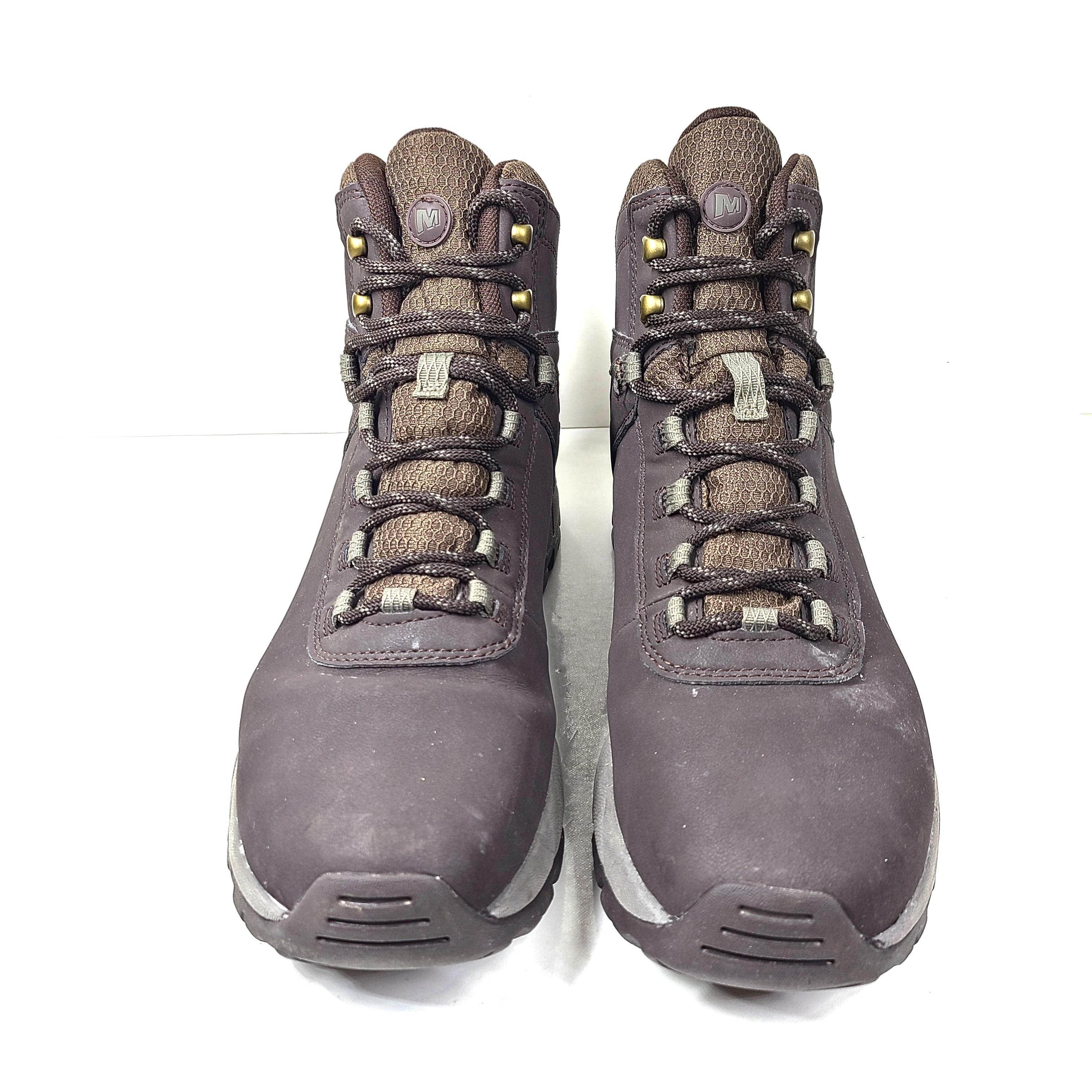 A pair of brown Merrell men's waterproof hiking boots on a rugged trail.