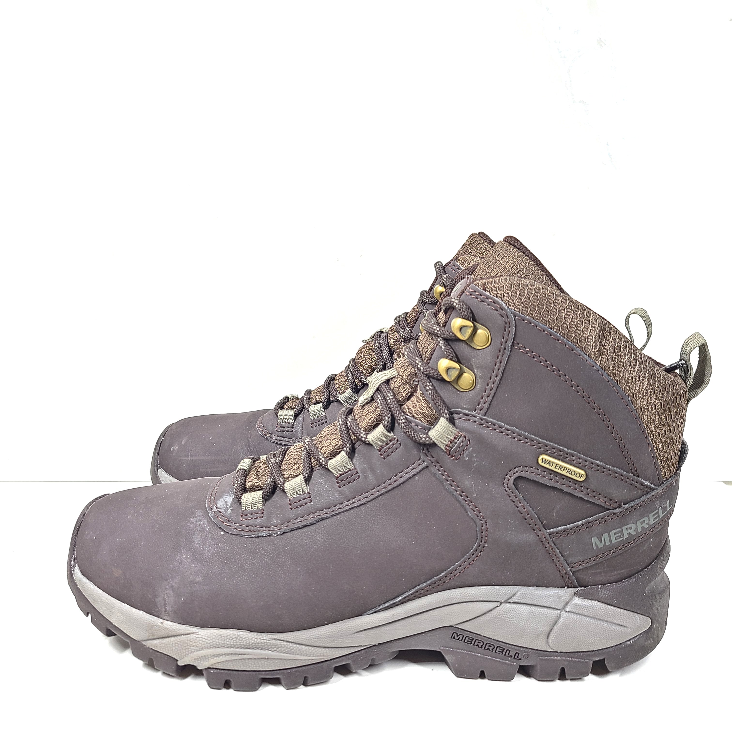 A pair of brown Merrell men's waterproof hiking boots on a rugged trail.