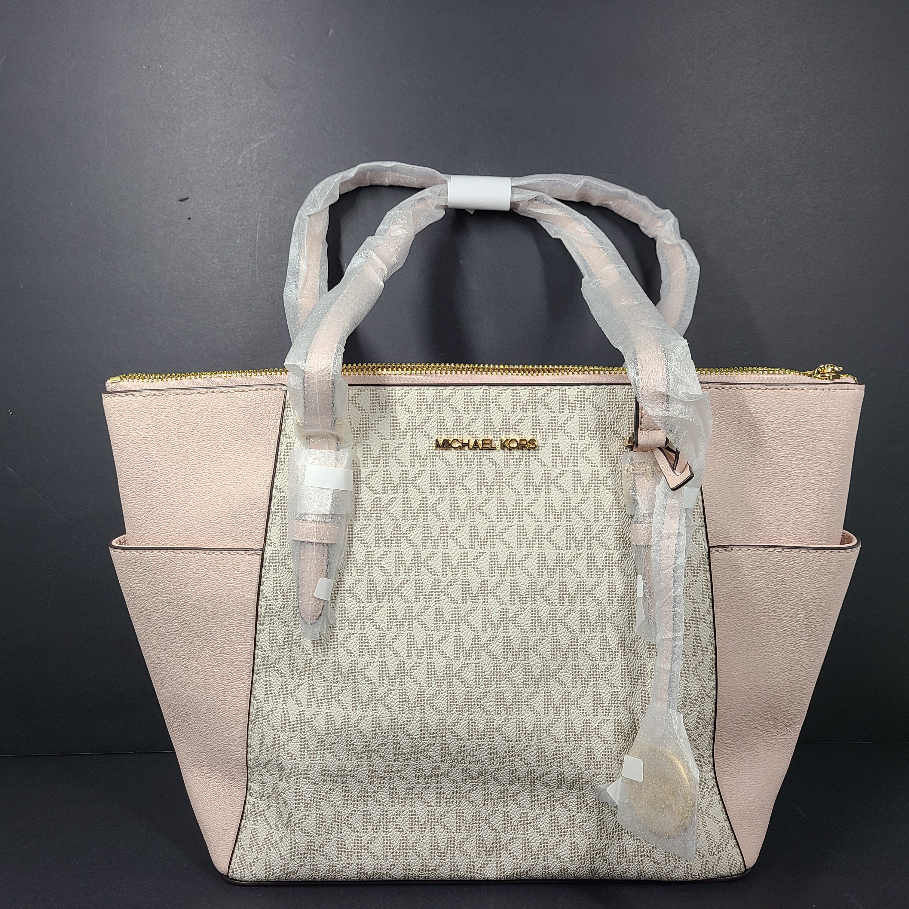 Light pink and logo canvas Michael Kors tote bag with gold zip and side pockets, shown with handles