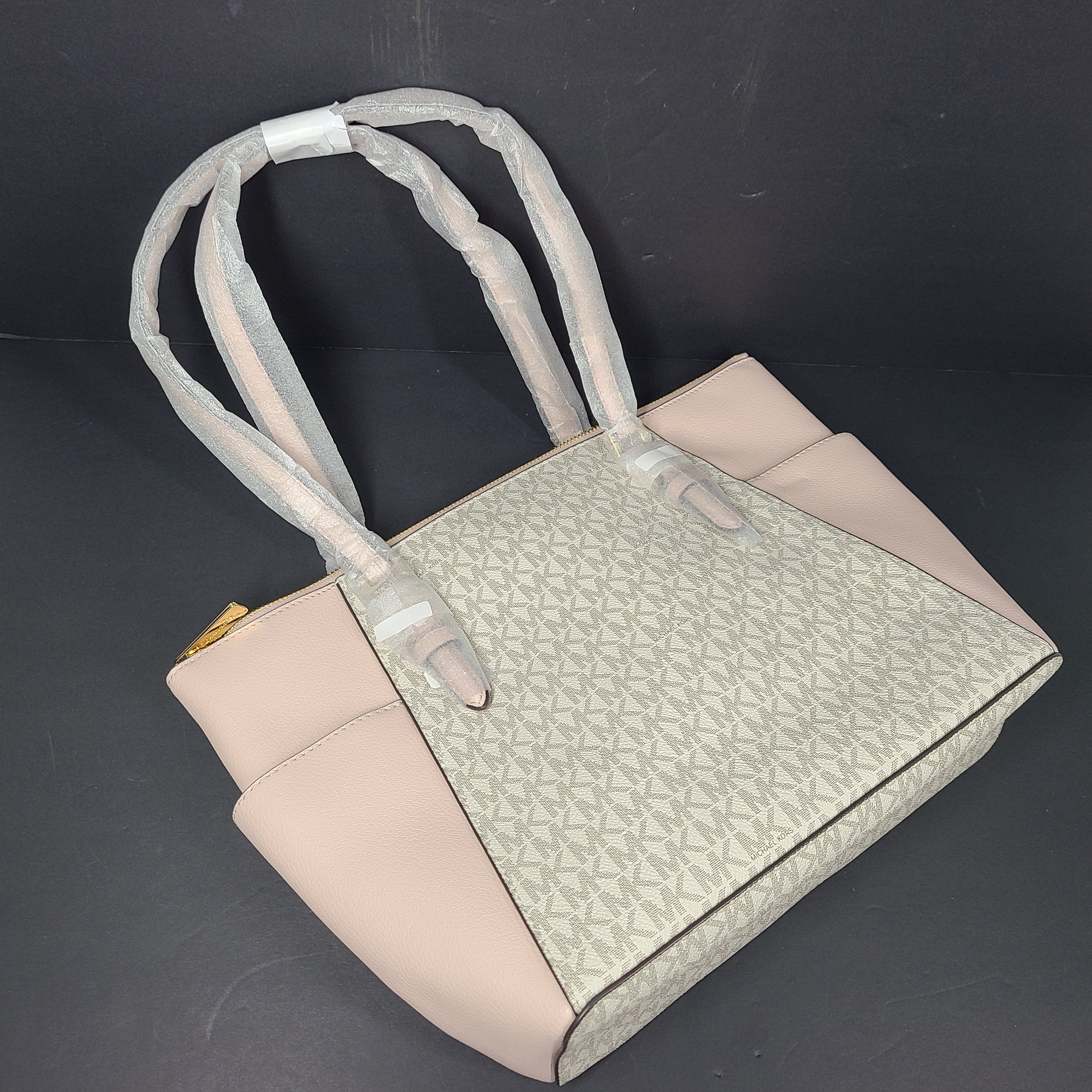 Light pink and logo canvas Michael Kors tote bag with gold zip and side pockets, shown with handles