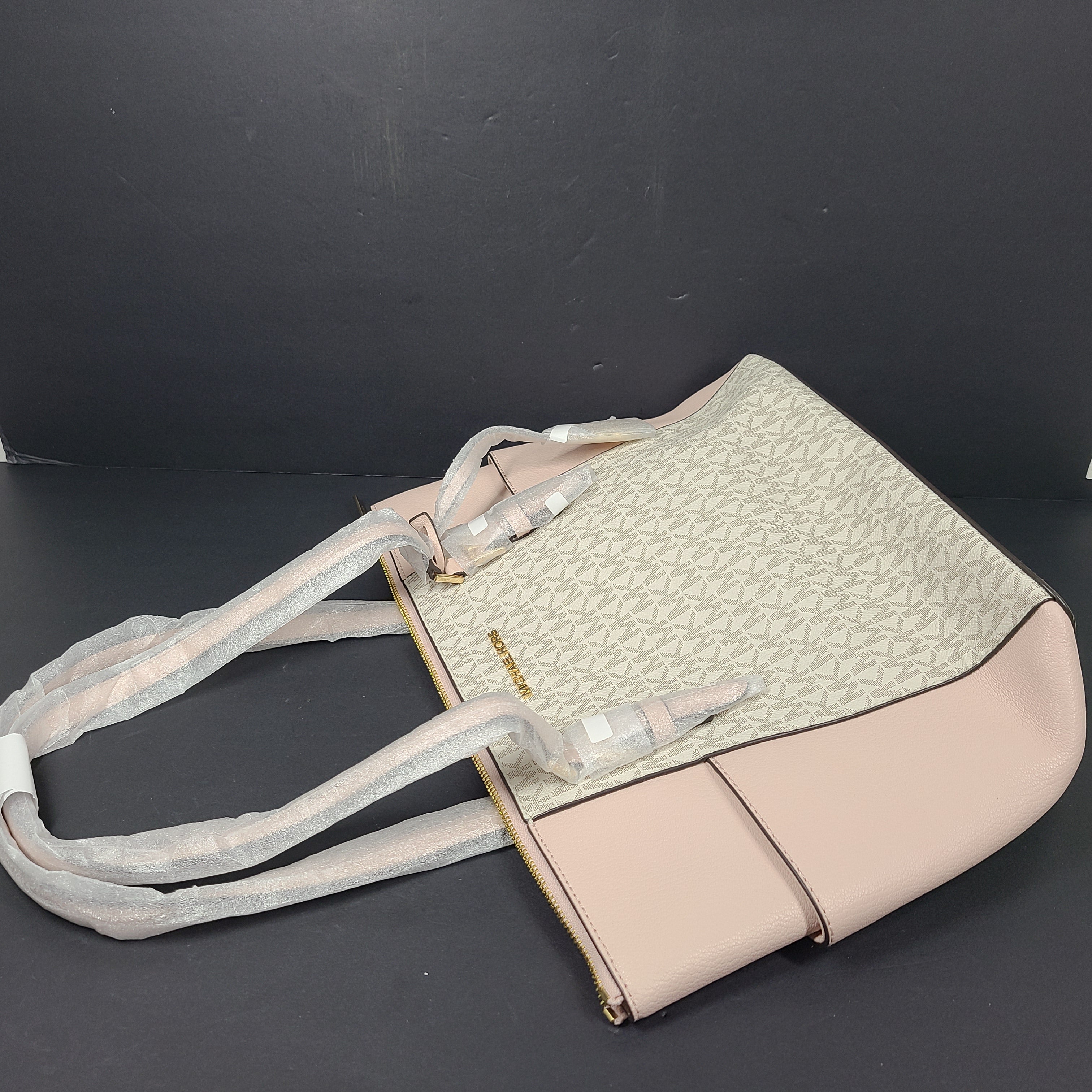 Light pink and logo canvas Michael Kors tote bag with gold zip and side pockets, shown with handles