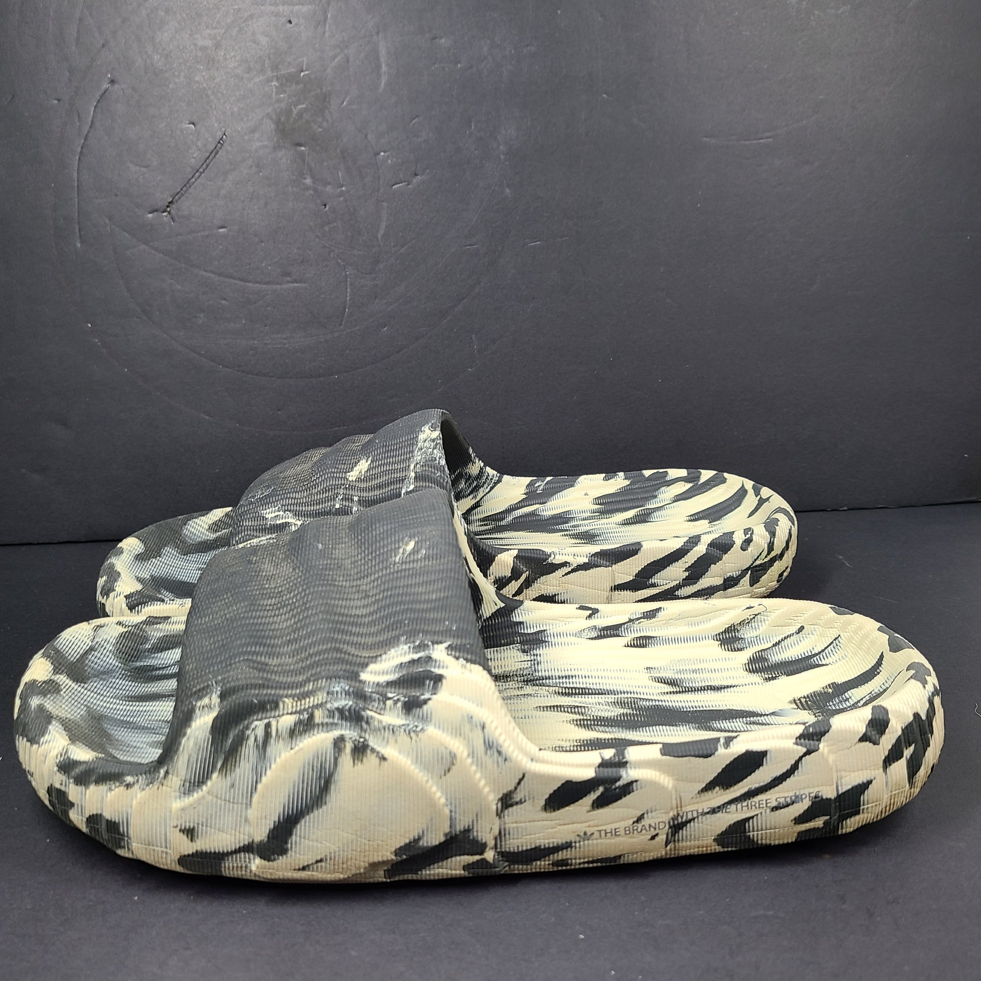 A pair of Adidas Originals Adilette Slides in camo print for men.
