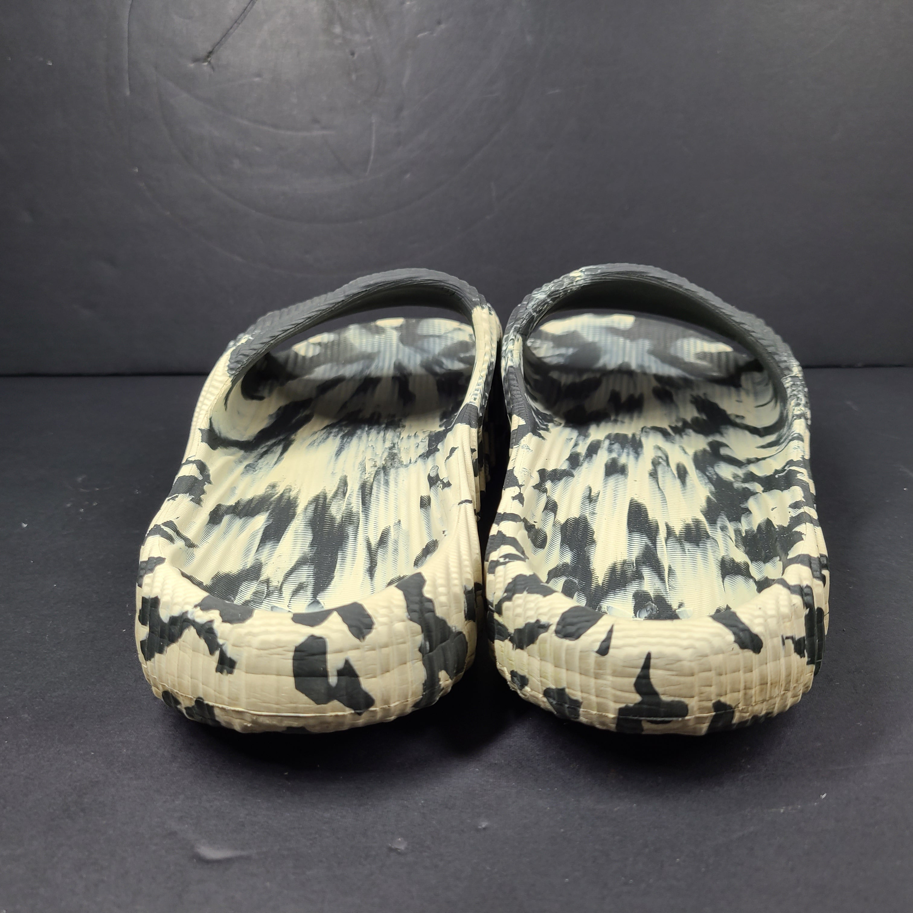 A pair of Adidas Originals Adilette Slides in camo print for men.