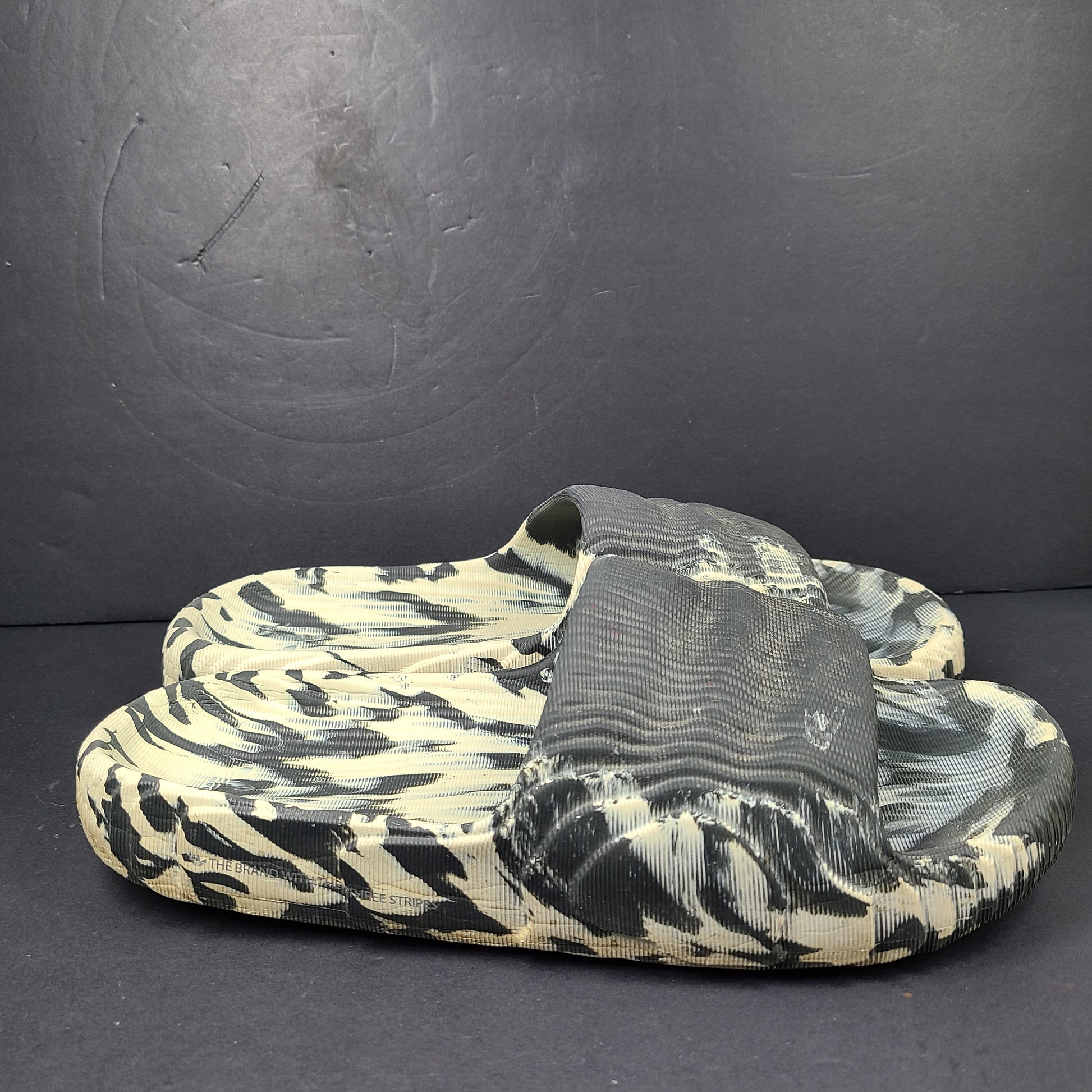 A pair of Adidas Originals Adilette Slides in camo print for men.
