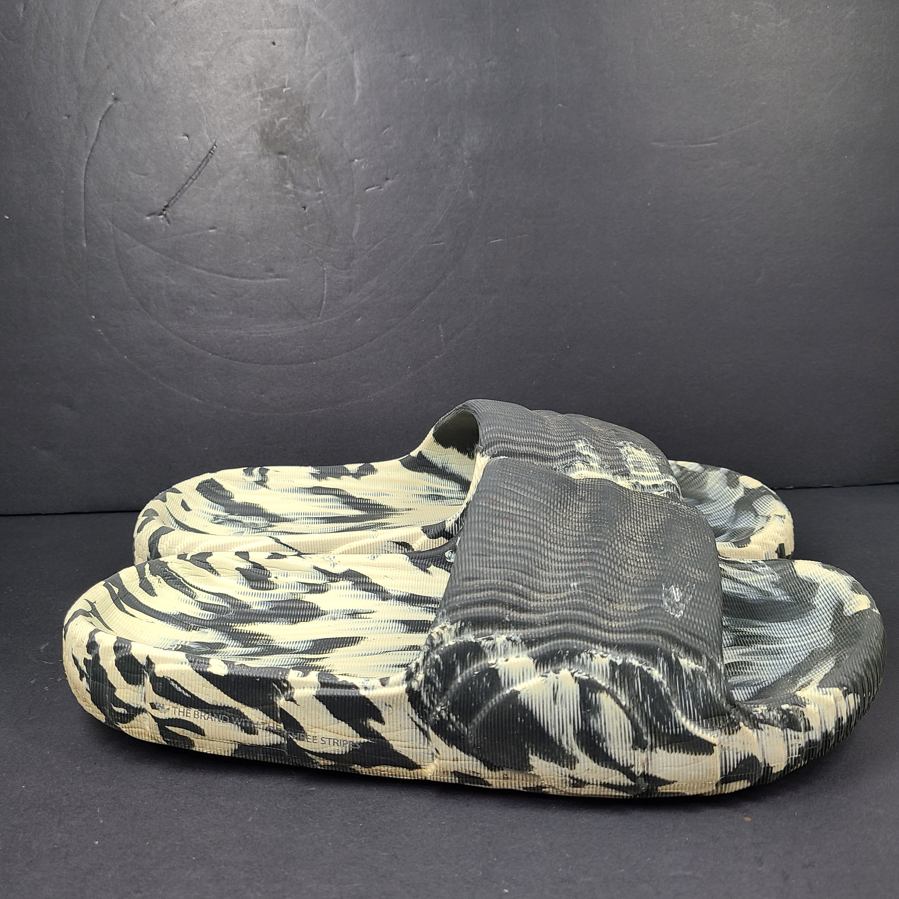 A pair of Adidas Originals Adilette Slides in camo print for men.