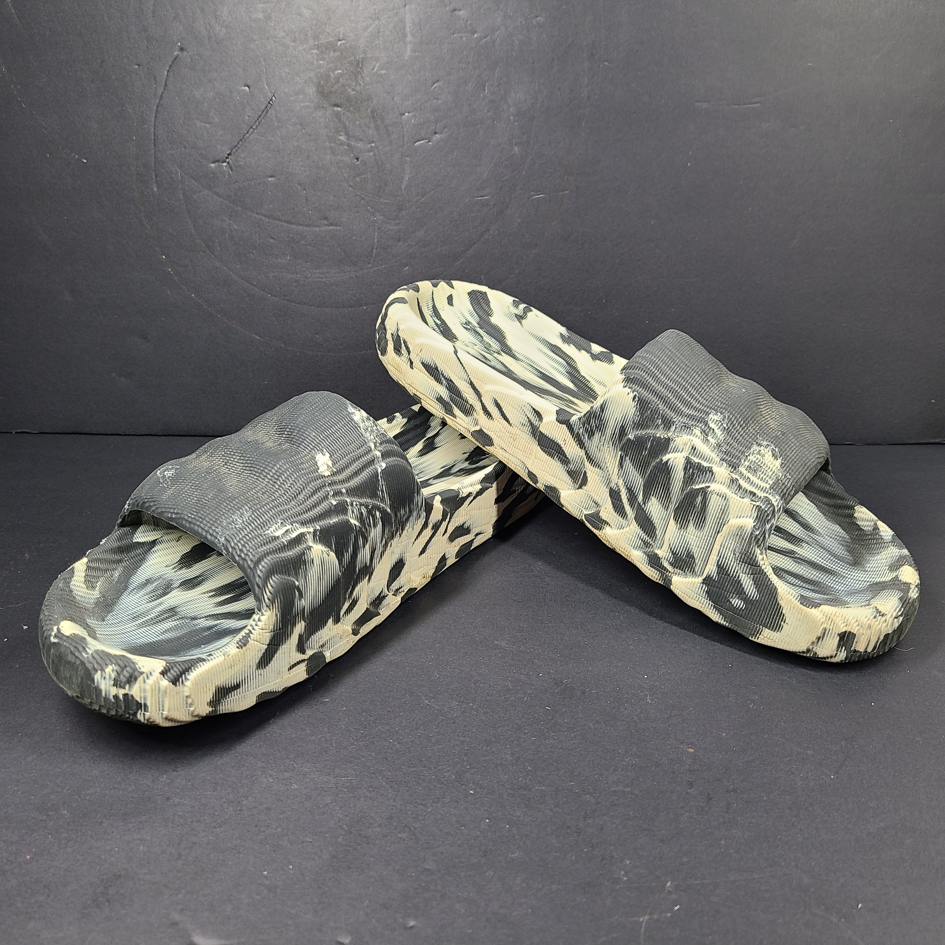 A pair of Adidas Originals Adilette Slides in camo print for men.
