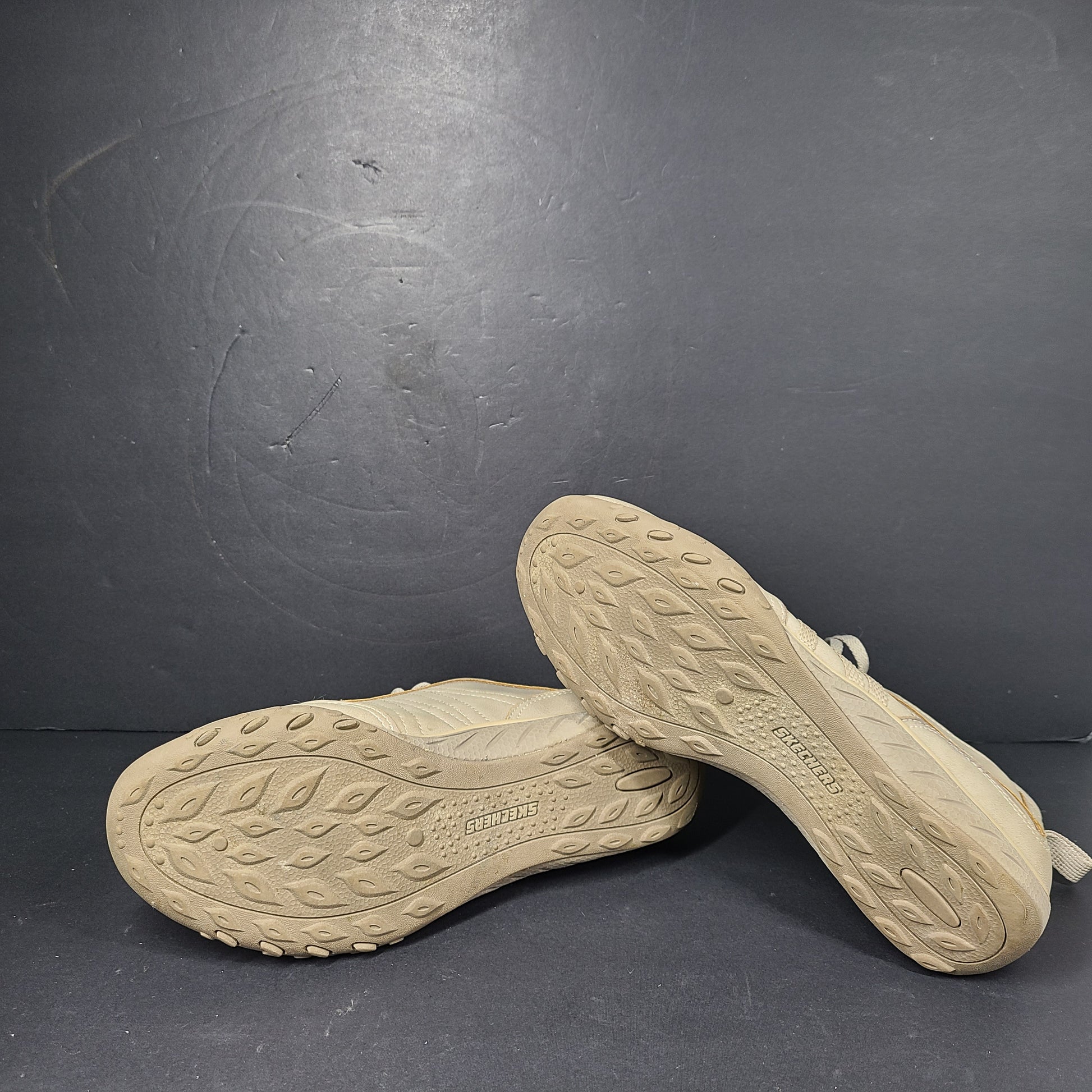 A pair of beige Skechers women's sneakers with a relaxed fit design.