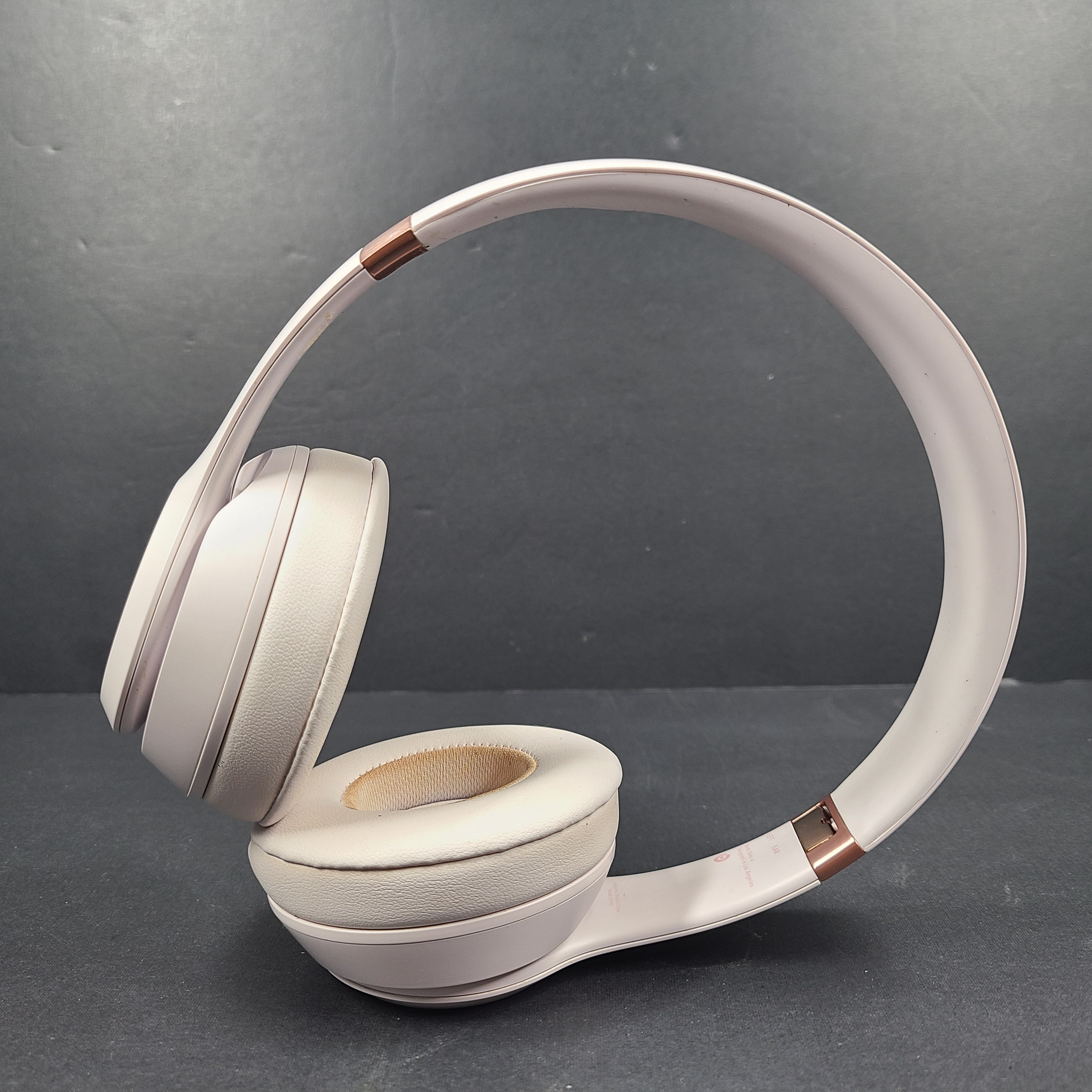 A pair of stylish on-ear headphones in white and rose gold
