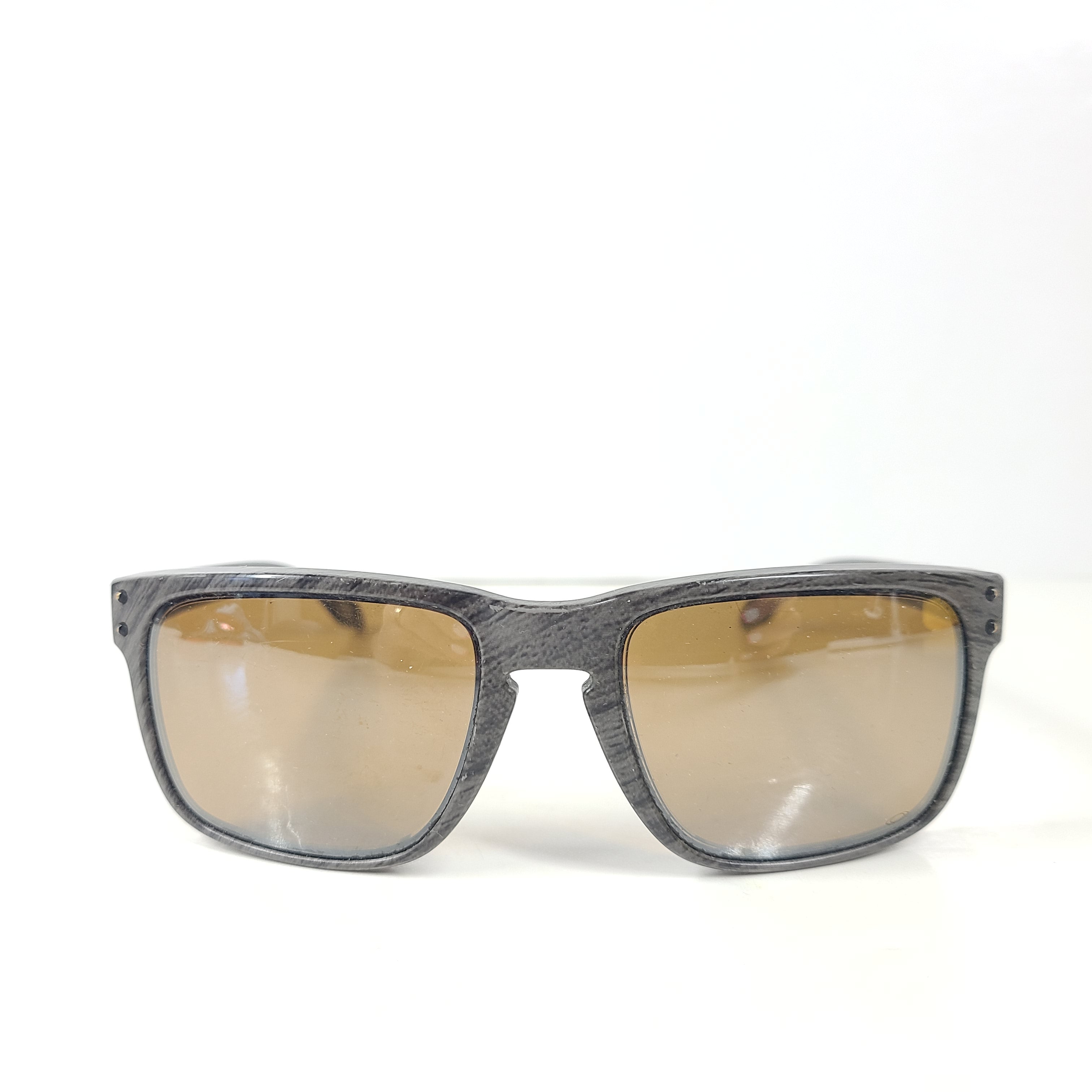 A stylish pair of Oakley Holbrook sunglasses in woodgrain with Prizm daily polarized lenses.