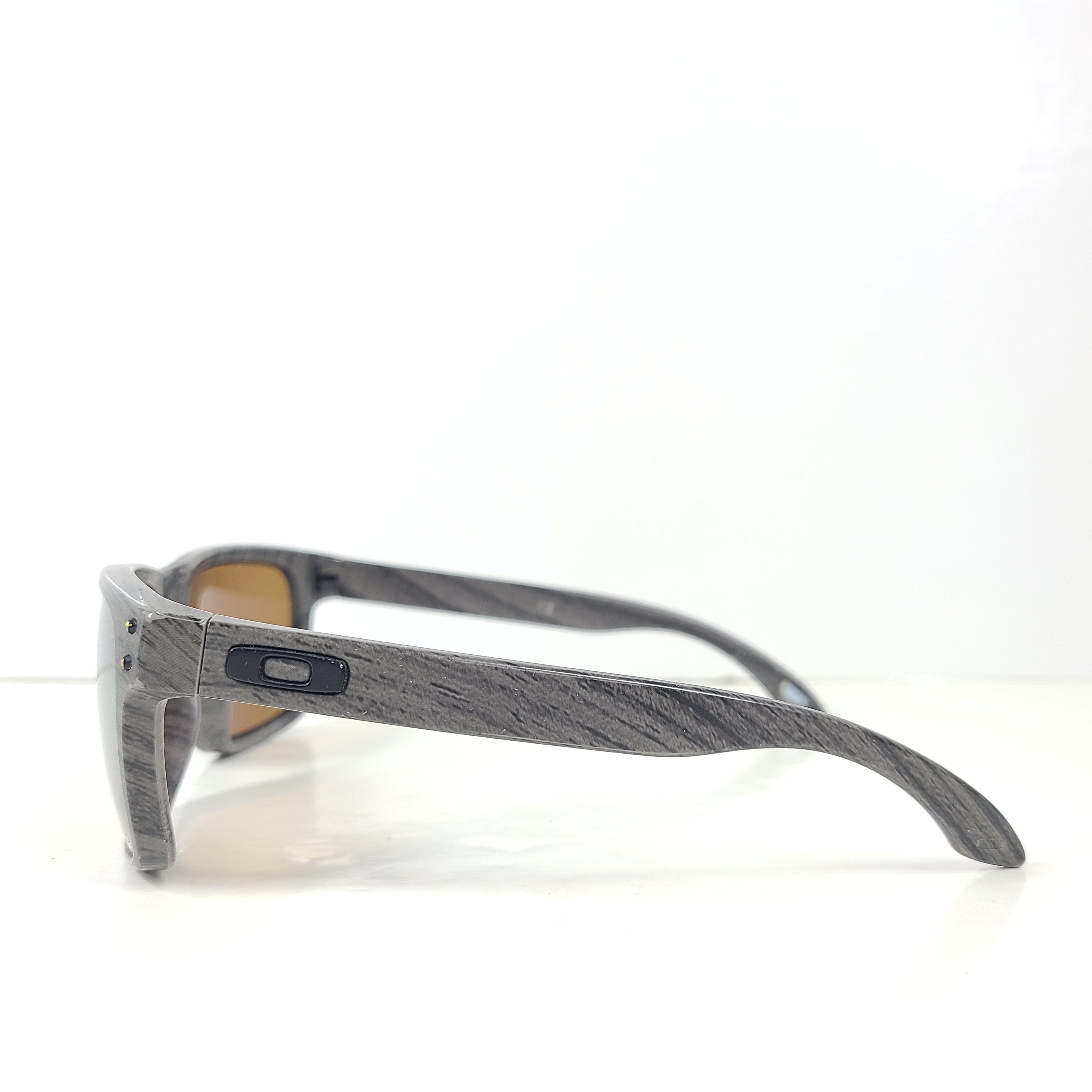 A stylish pair of Oakley Holbrook sunglasses in woodgrain with Prizm daily polarized lenses.
