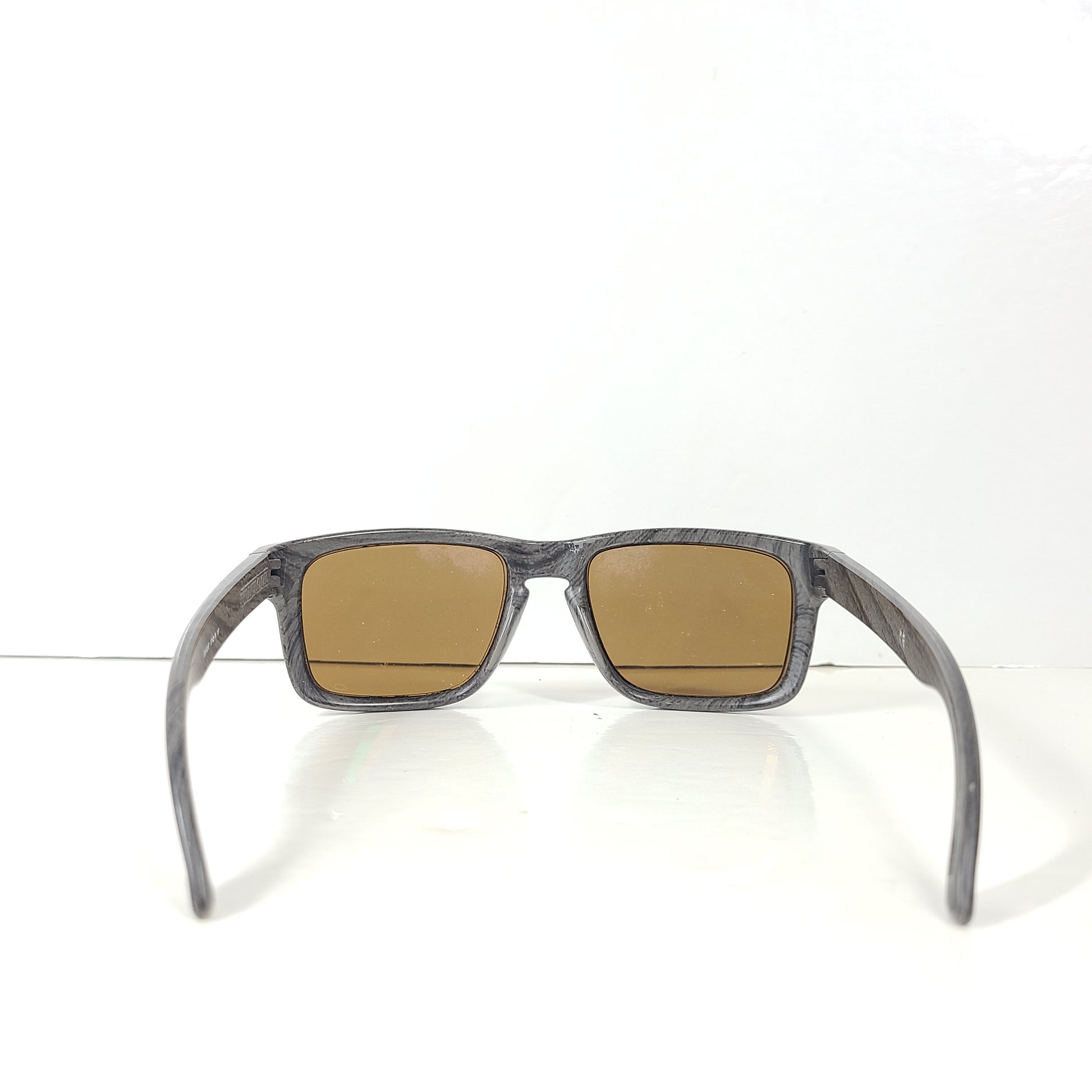 A stylish pair of Oakley Holbrook sunglasses in woodgrain with Prizm daily polarized lenses.