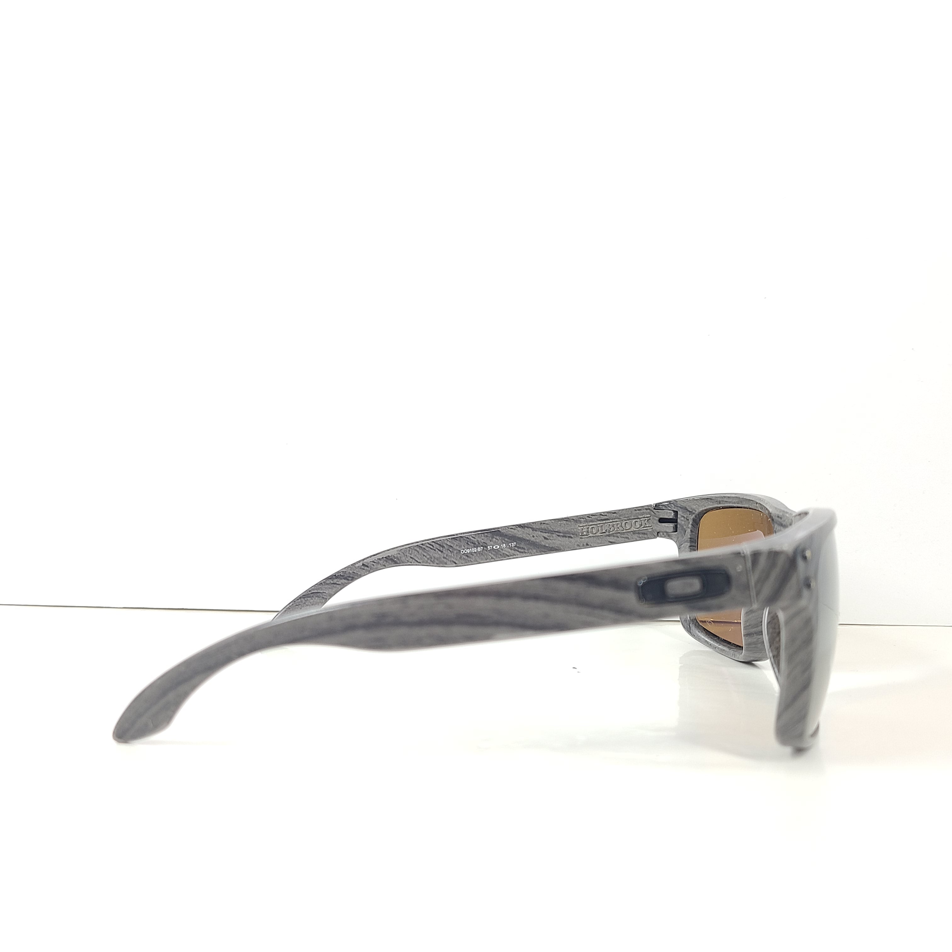 A stylish pair of Oakley Holbrook sunglasses in woodgrain with Prizm daily polarized lenses.