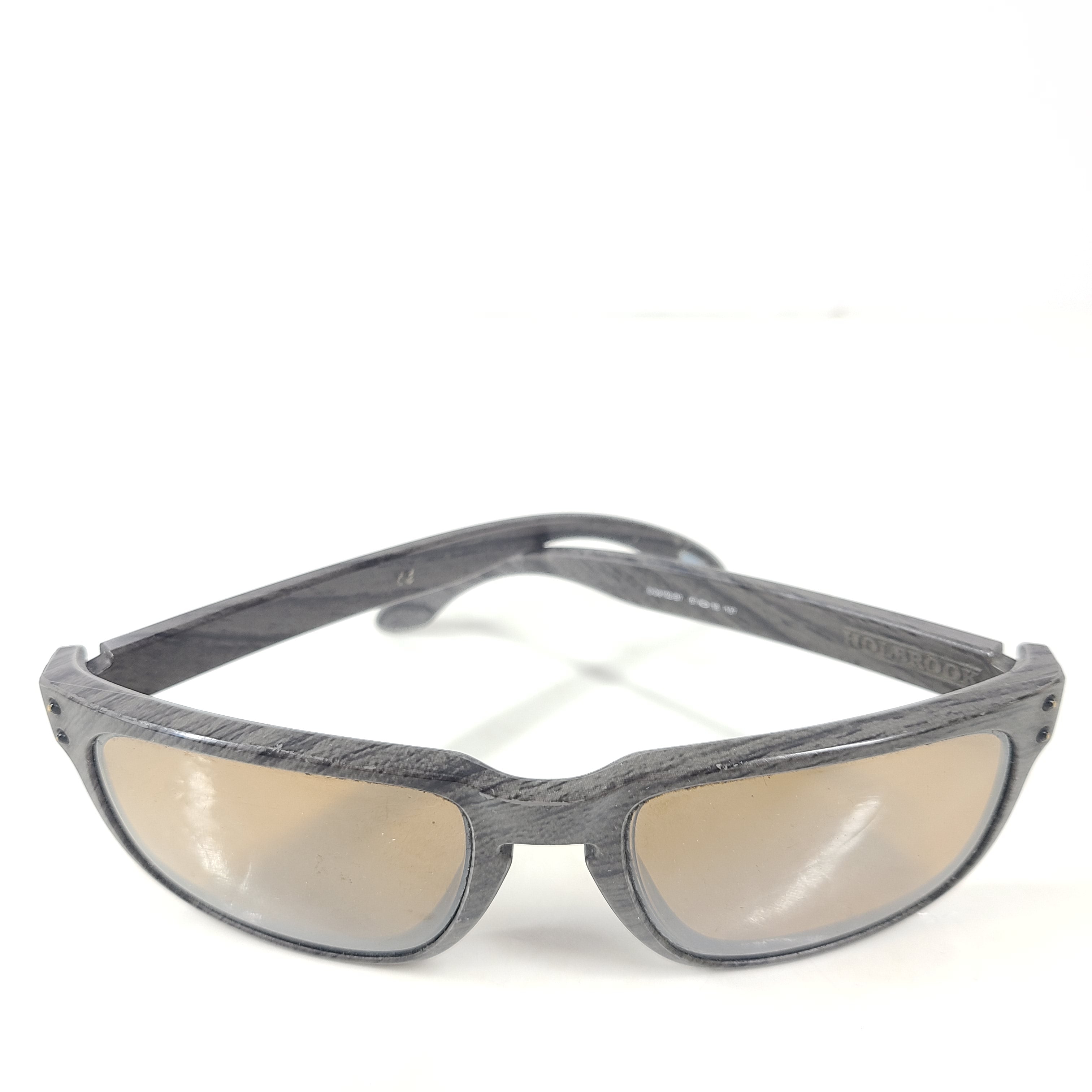 A stylish pair of Oakley Holbrook sunglasses in woodgrain with Prizm daily polarized lenses.
