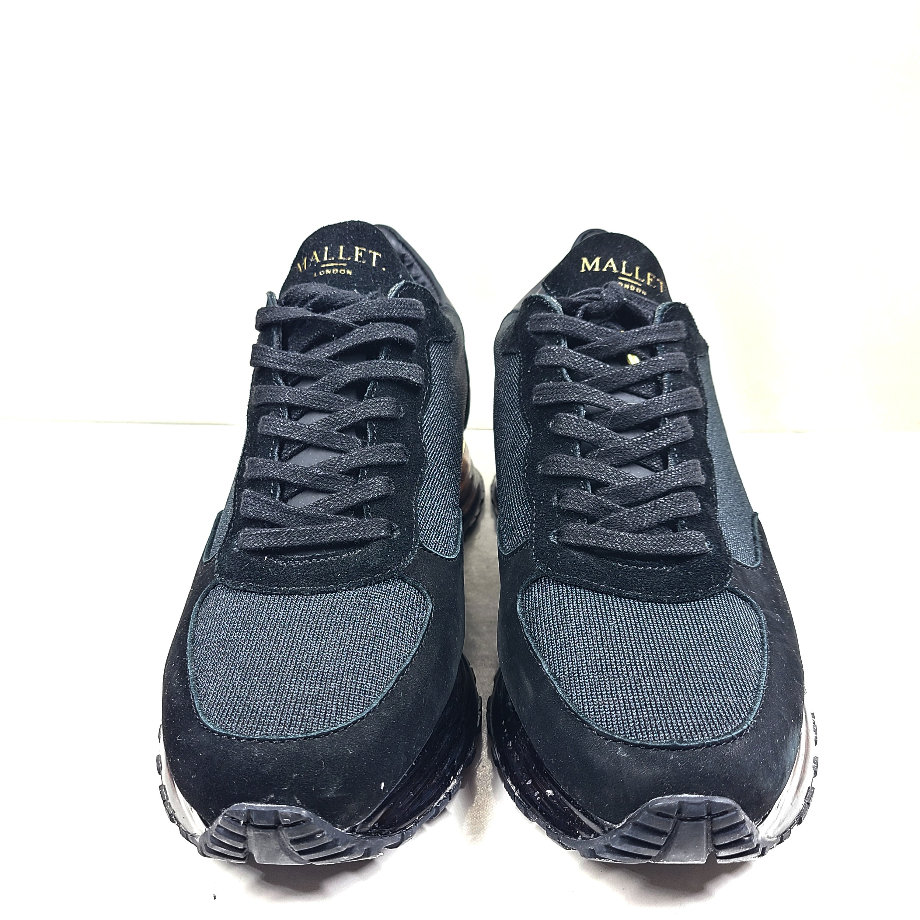 A pair of sleek black and gold Mallet London sneakers