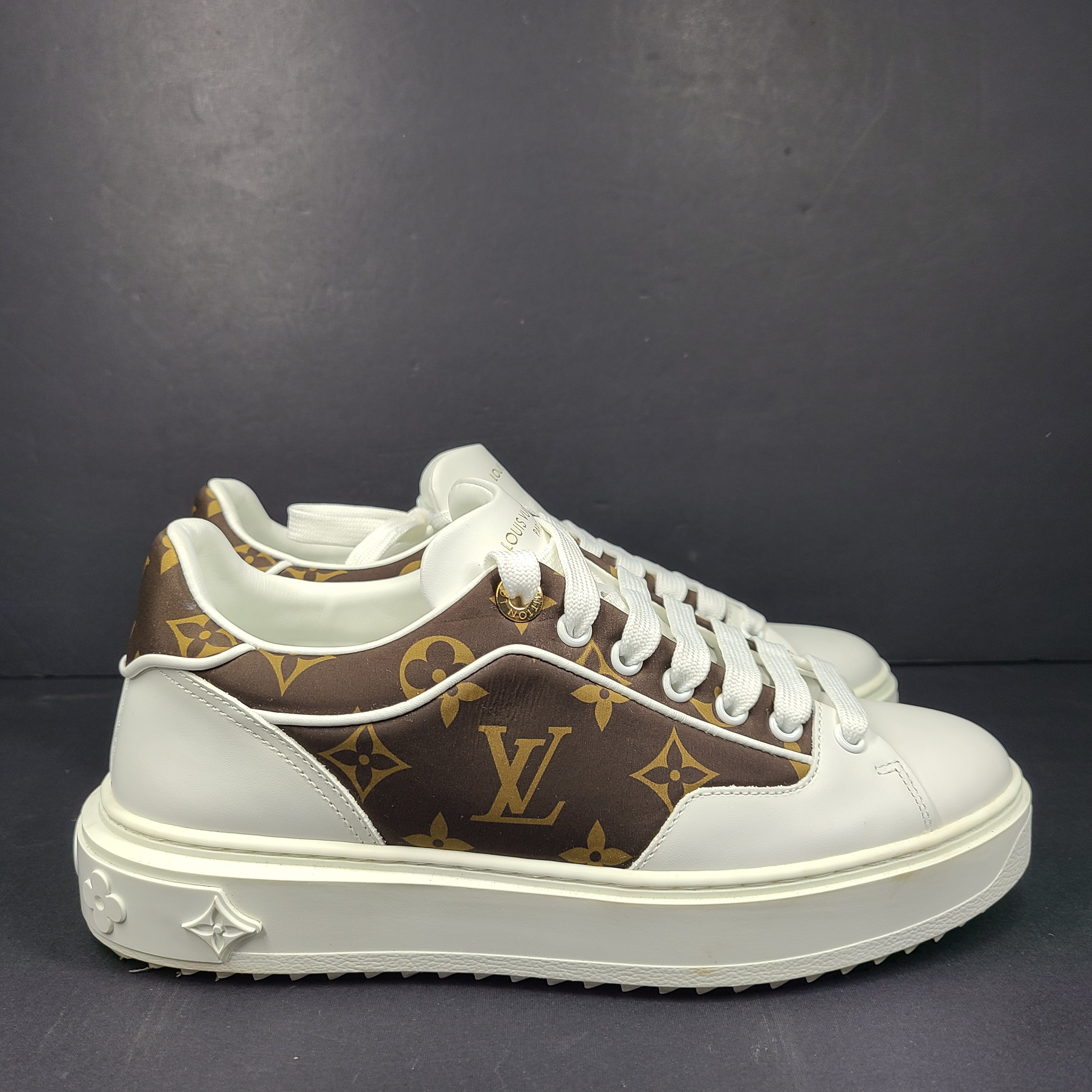 A pair of Louis Vuitton LV Monogram sneakers in white and brown.