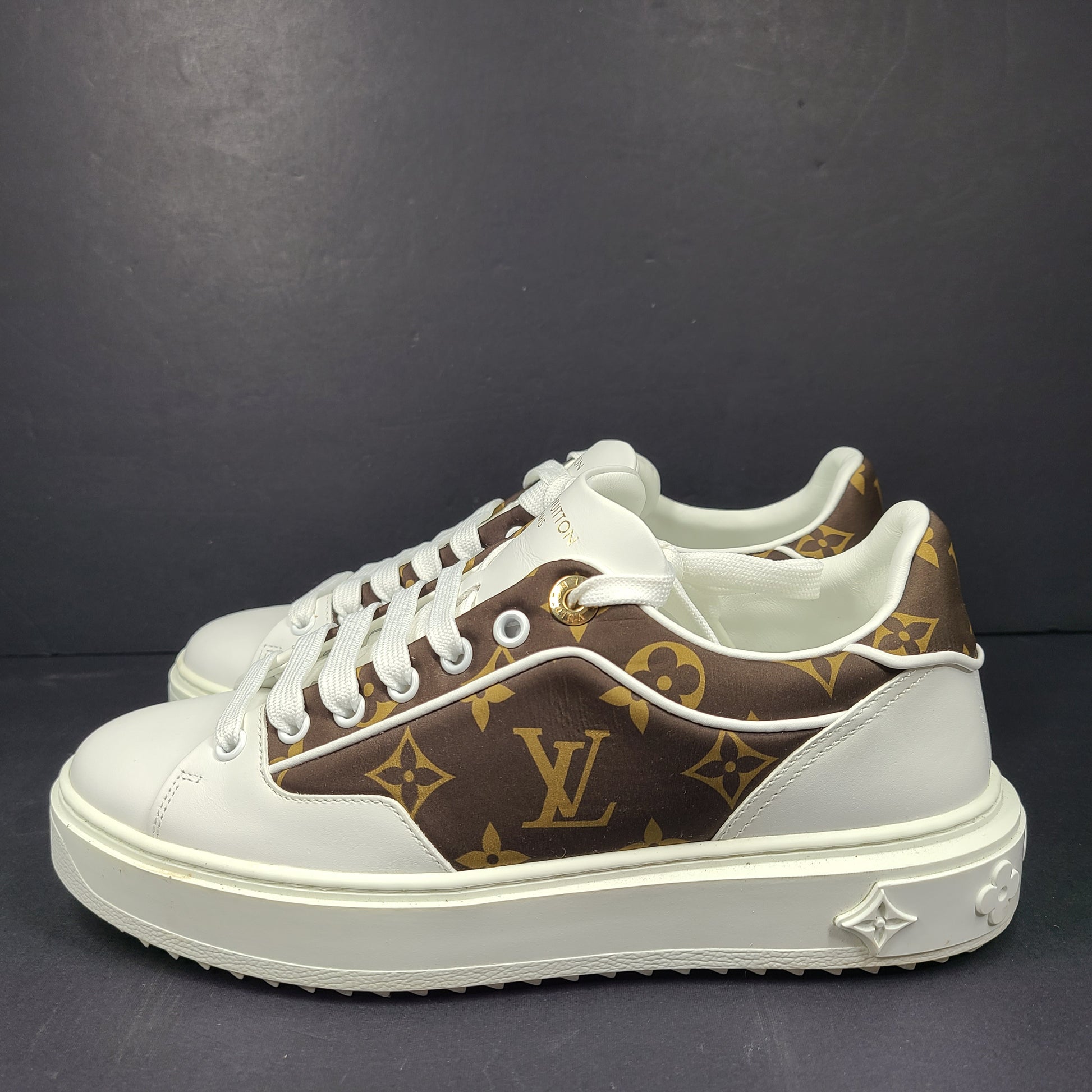 A pair of Louis Vuitton LV Monogram sneakers in white and brown.
