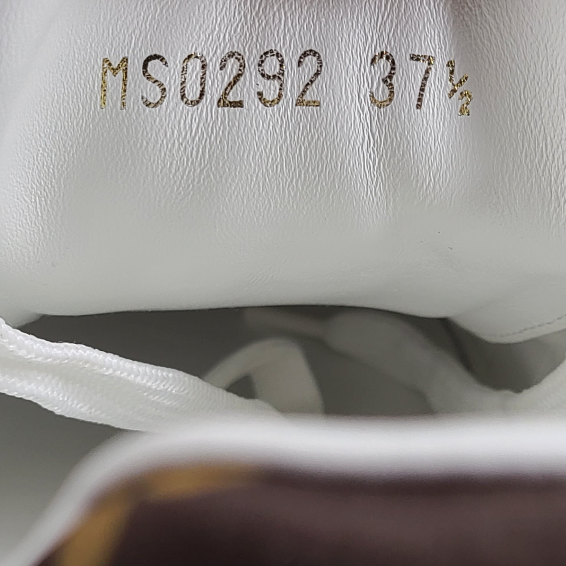 A pair of Louis Vuitton LV Monogram sneakers in white and brown.