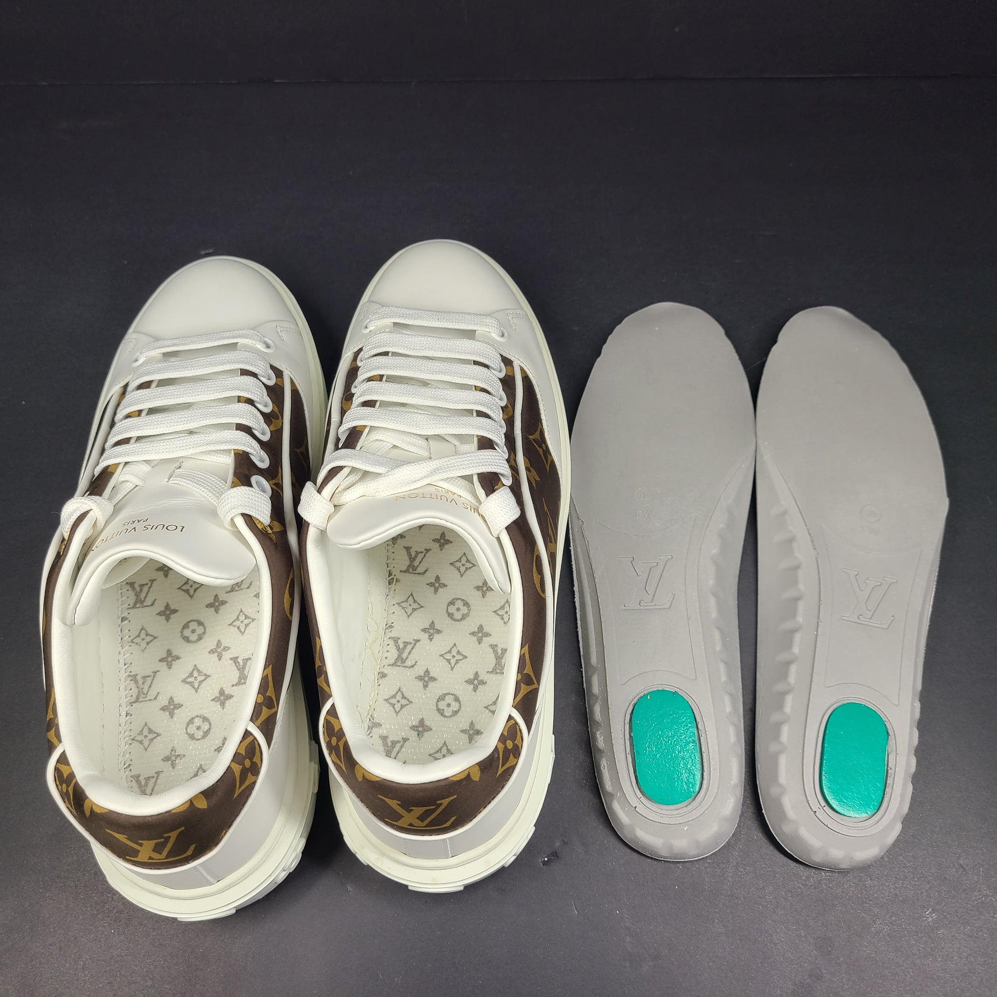 A pair of Louis Vuitton LV Monogram sneakers in white and brown.
