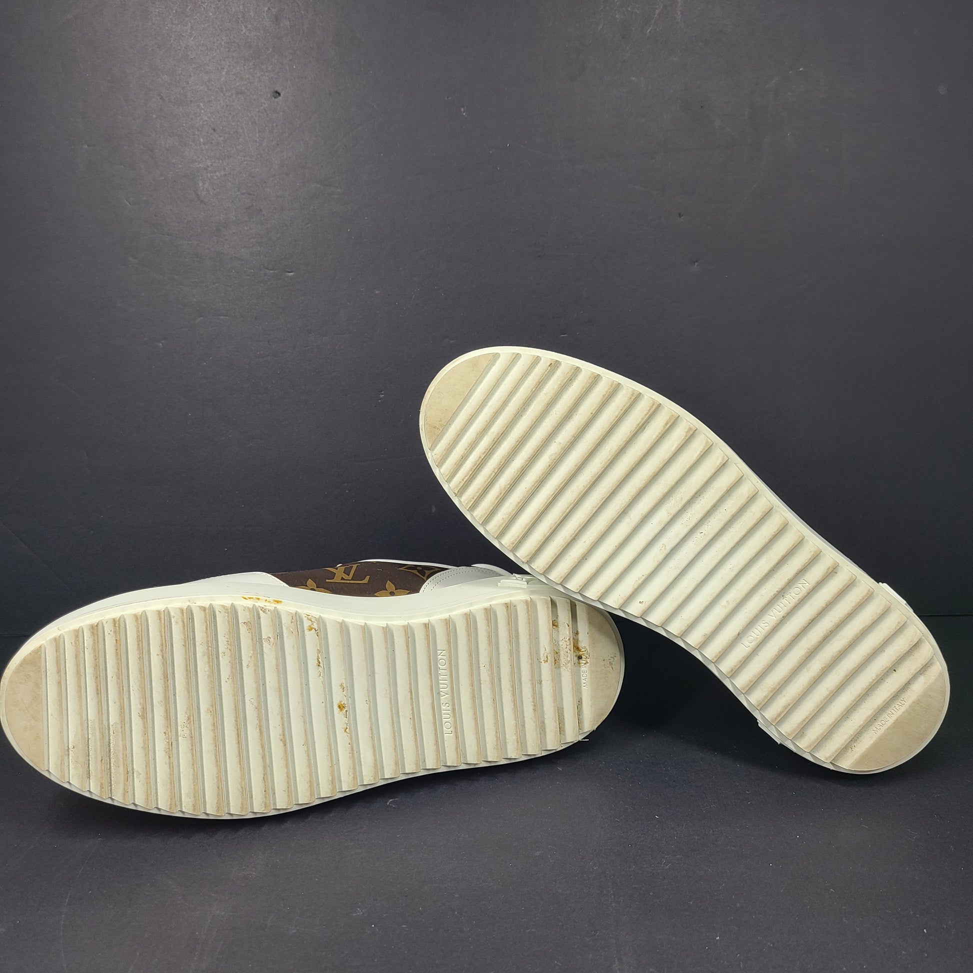A pair of Louis Vuitton LV Monogram sneakers in white and brown.