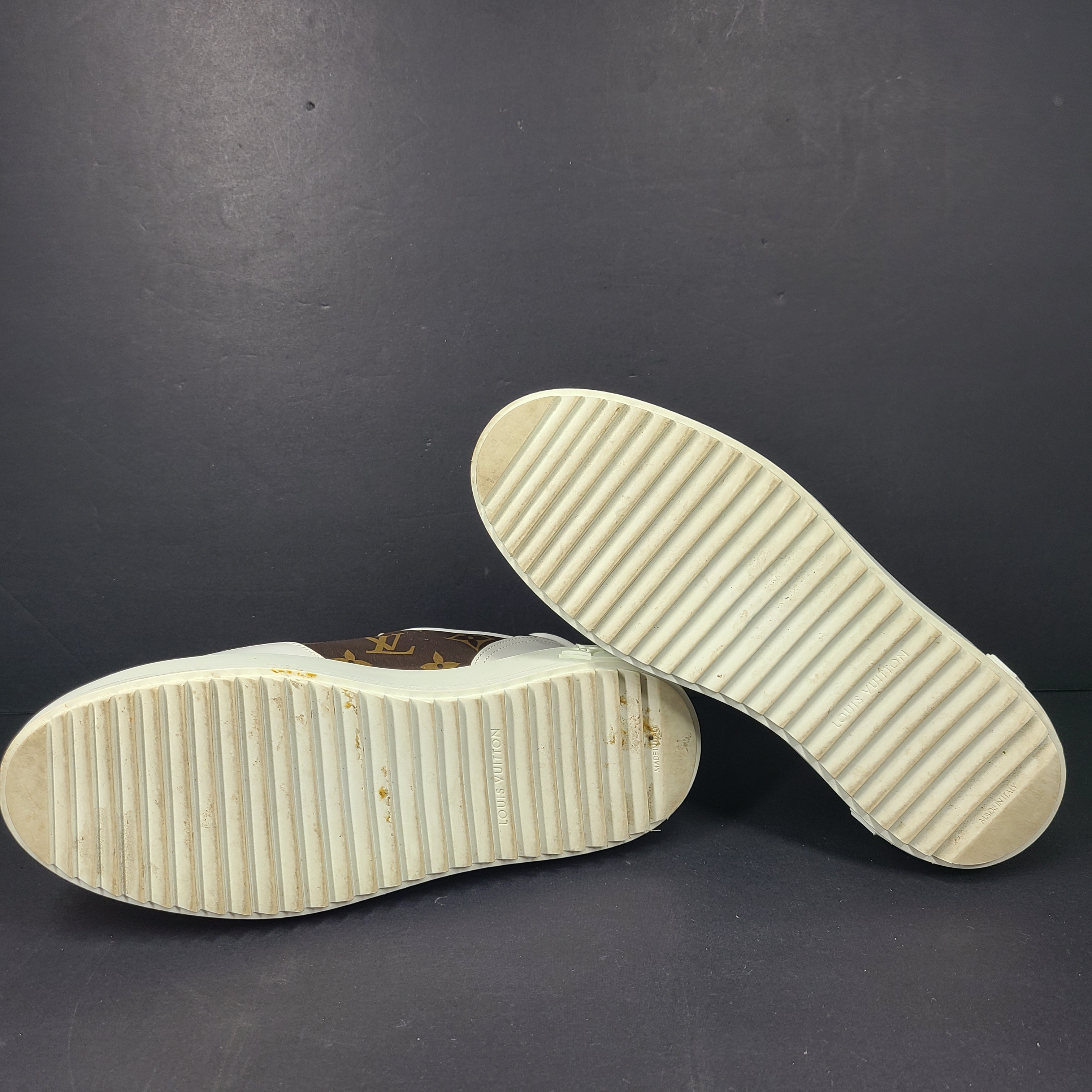 A pair of Louis Vuitton LV Monogram sneakers in white and brown.
