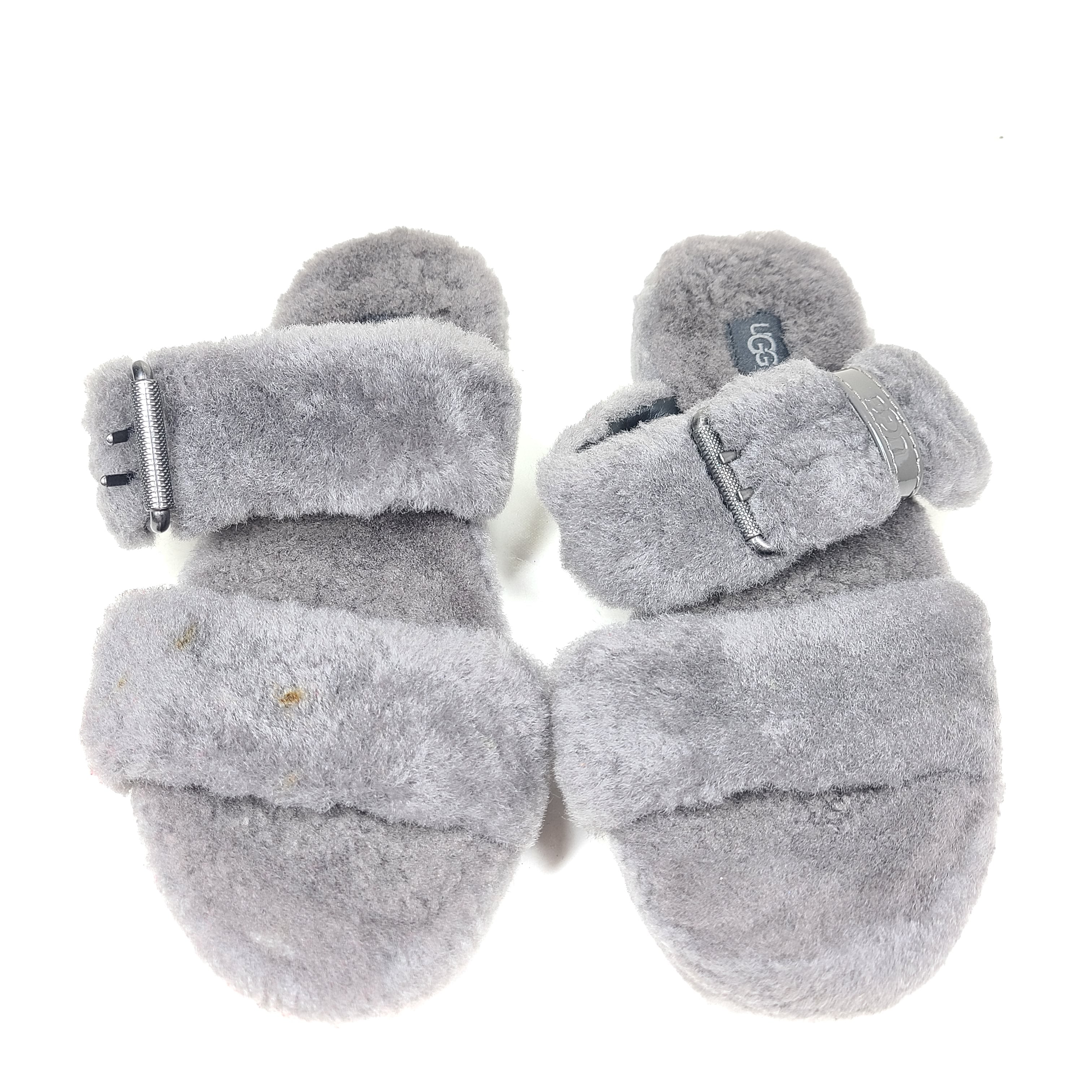 A pair of gray UGG Fluffy Sandals with adjustable straps in size 7.
