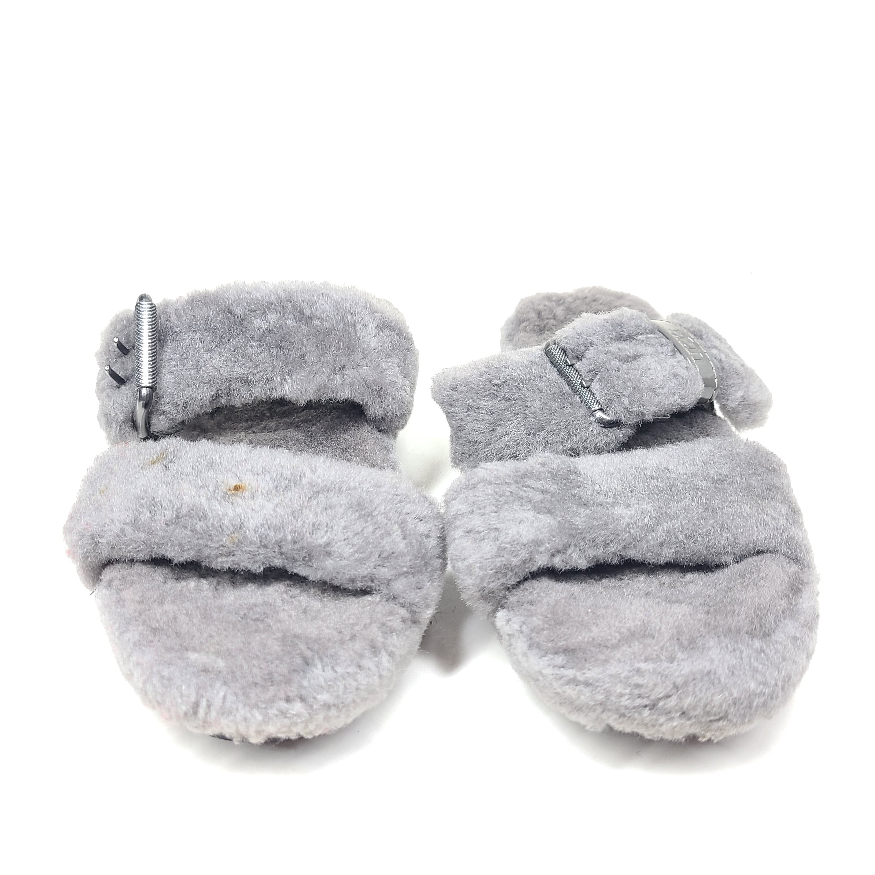 A pair of gray UGG Fluffy Sandals with adjustable straps in size 7.