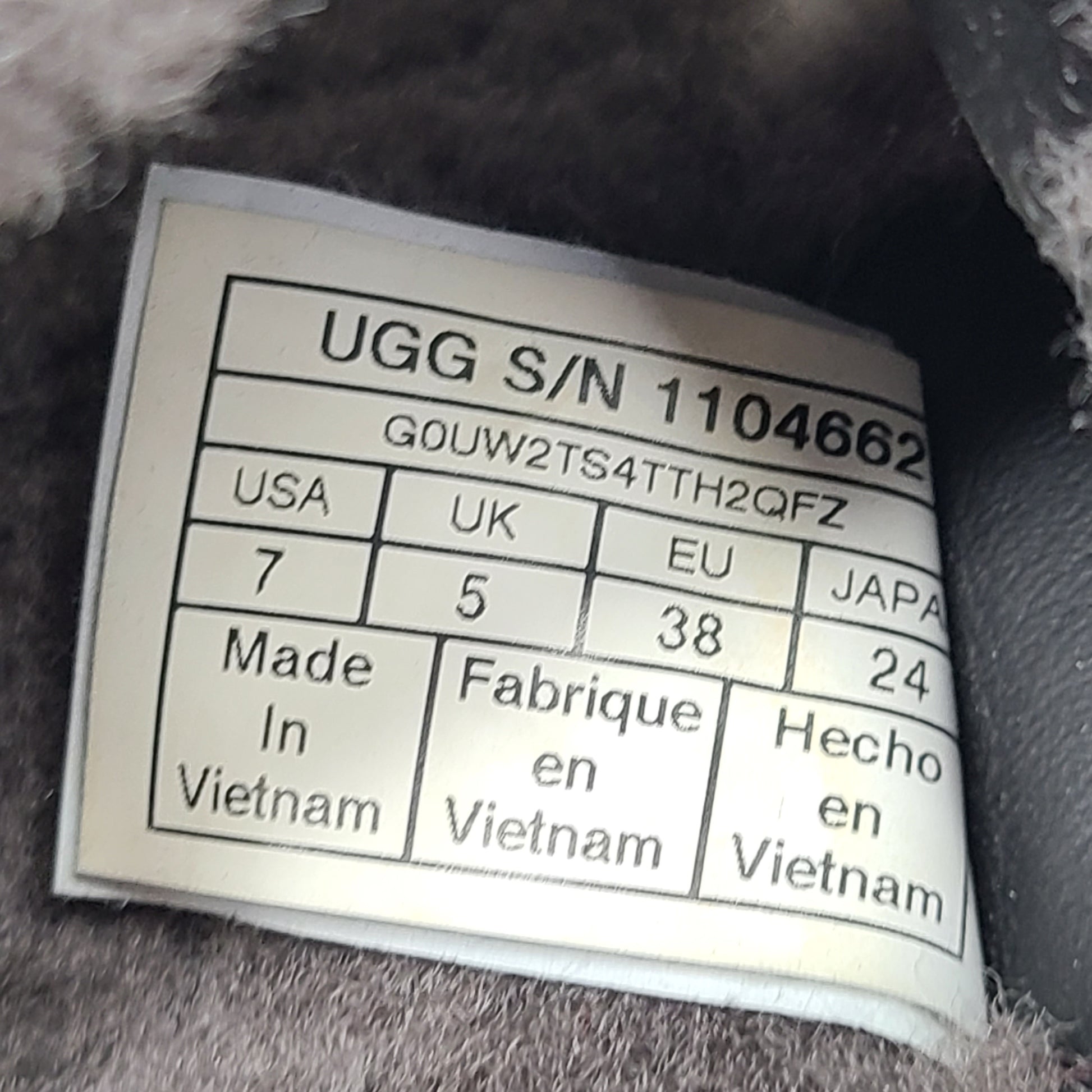 A pair of gray UGG Fluffy Sandals with adjustable straps in size 7.