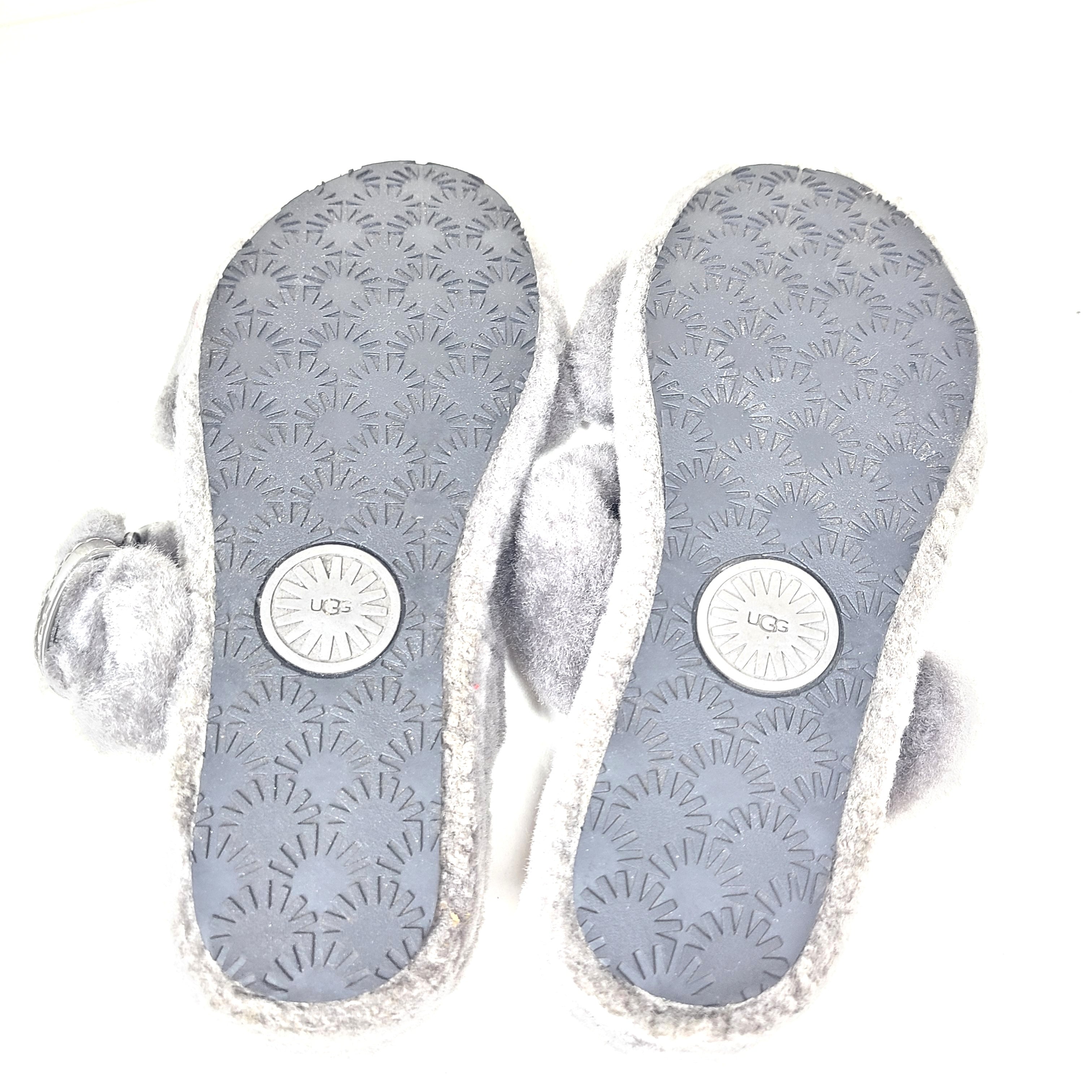 A pair of gray UGG Fluffy Sandals with adjustable straps in size 7.