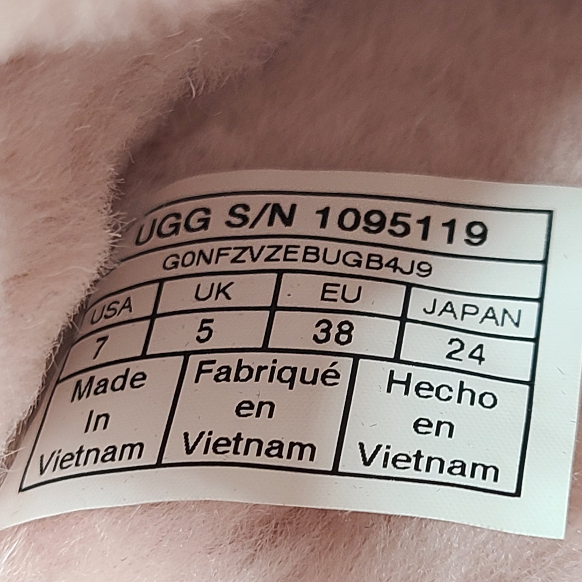 A pair of fluffy pink UGG slide slippers.