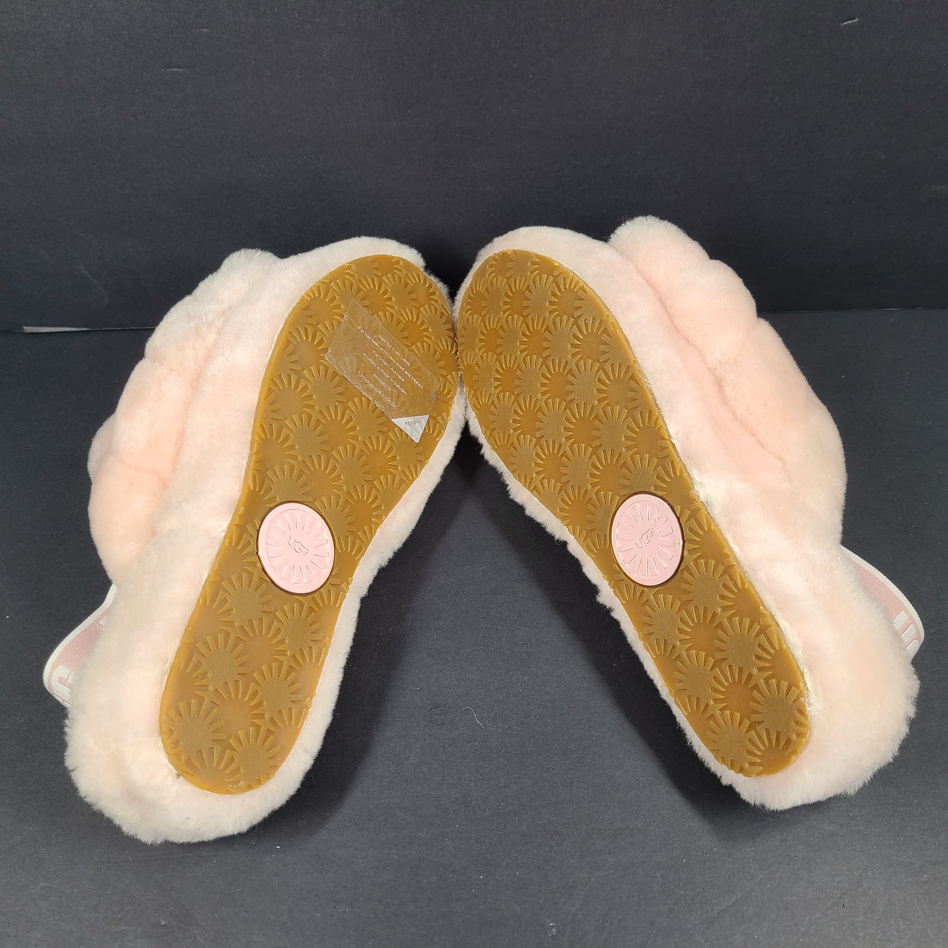 A pair of fluffy pink UGG slide slippers.