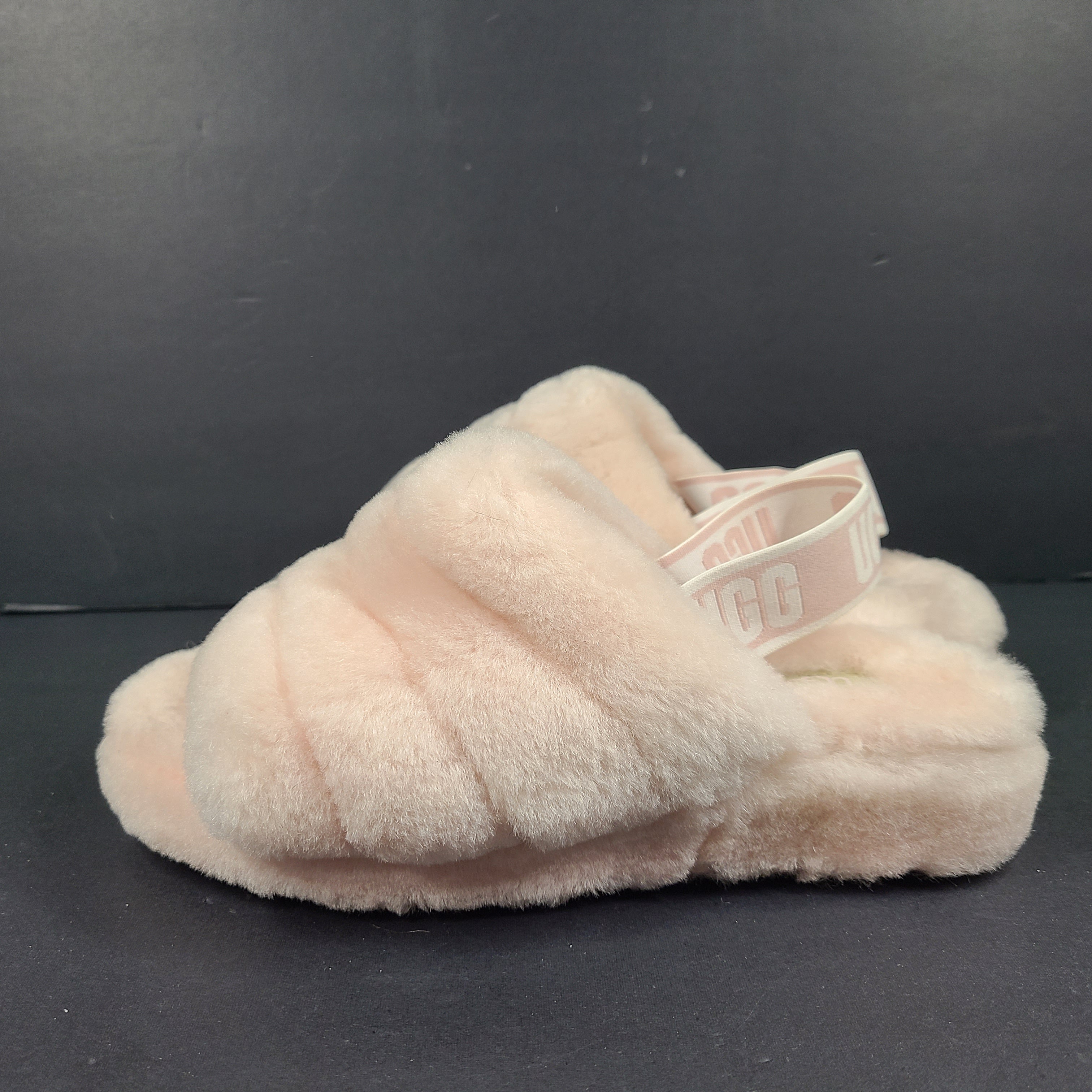 A pair of fluffy pink UGG slide slippers.