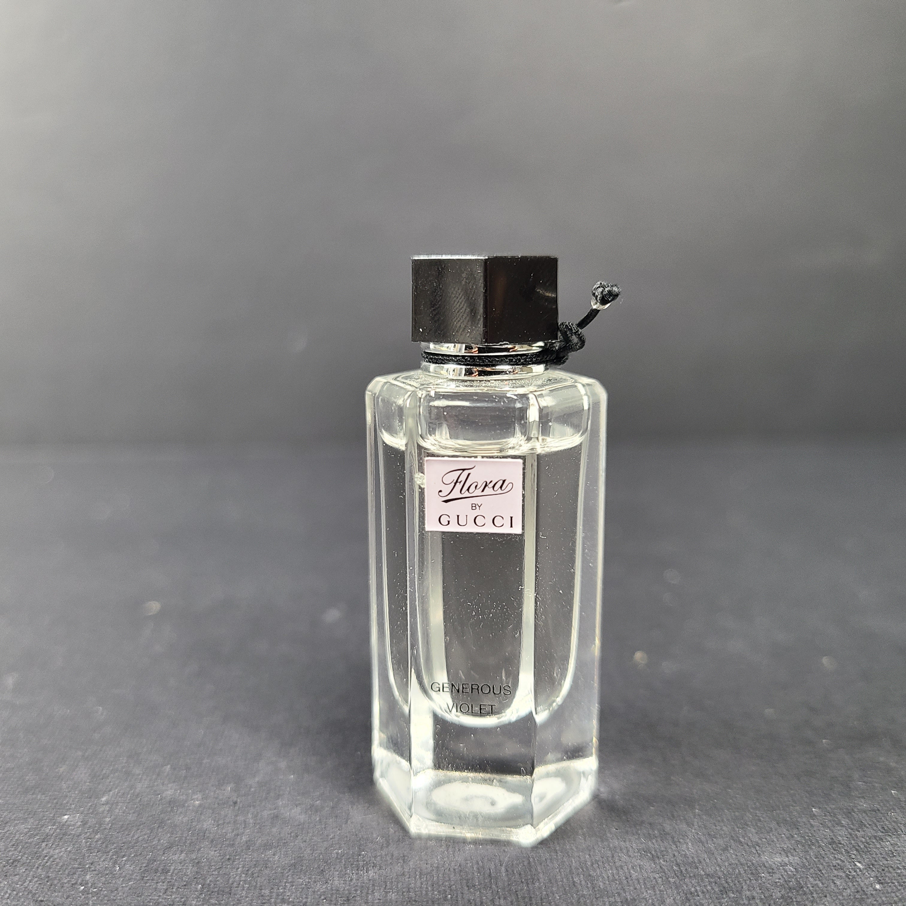 A small 5ml bottle of Gucci Flora Generous Violet Eau de Toilette perfume.