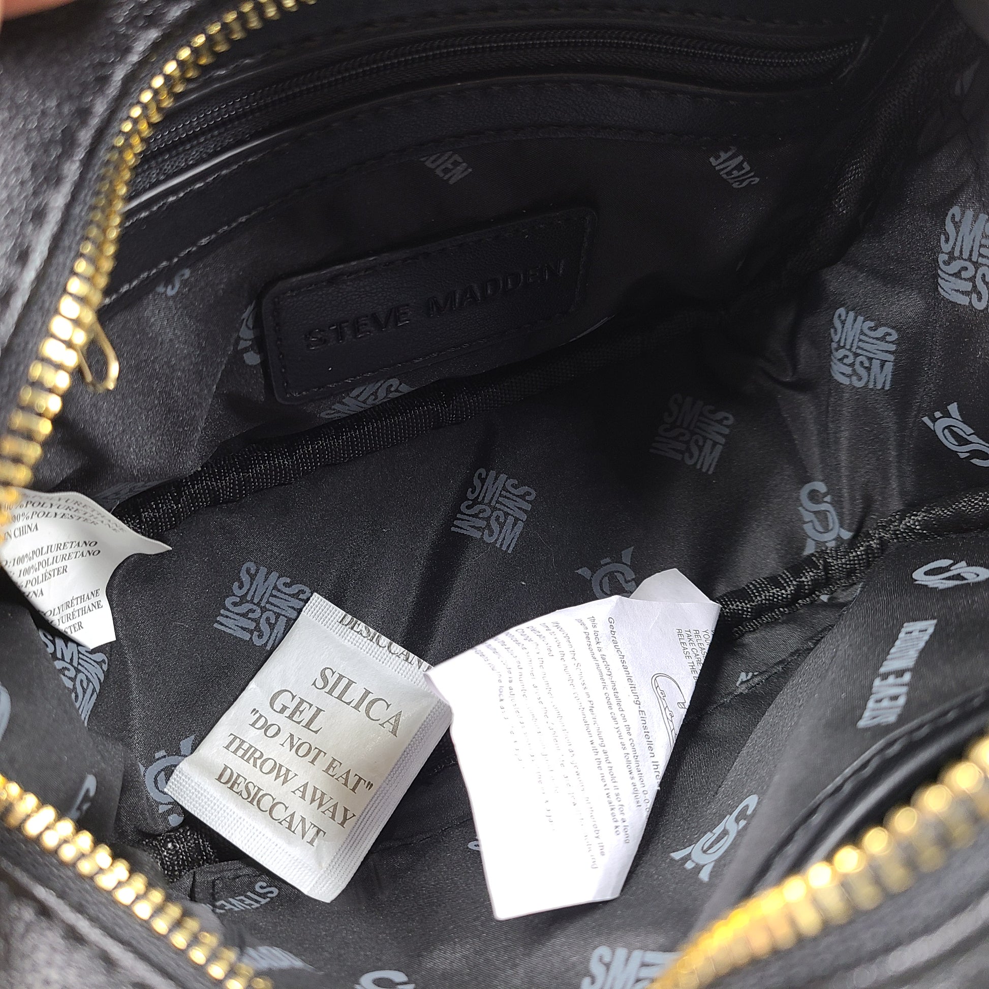 A stylish black crossbody bag with a detachable pouch and gold chain strap.