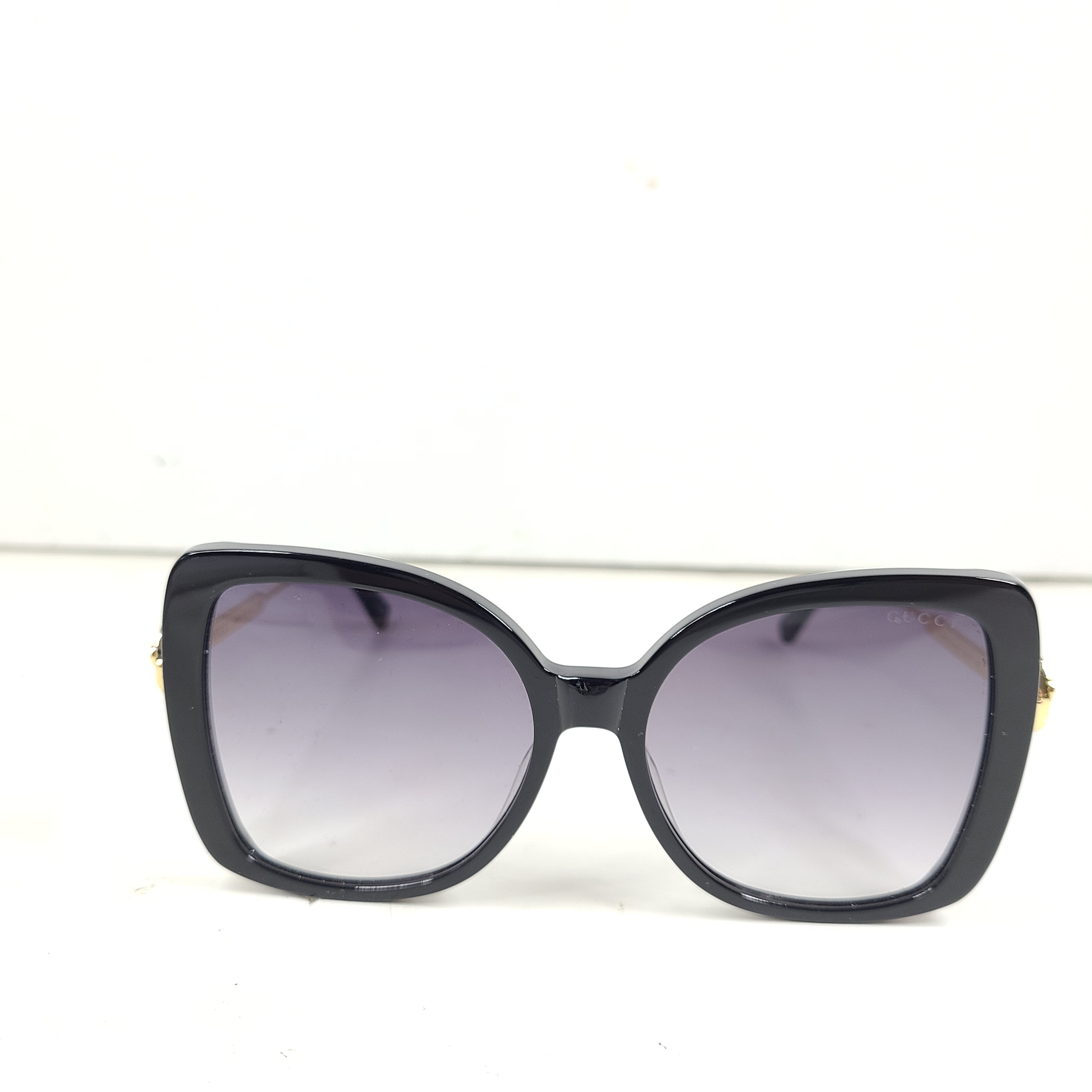 A stylish pair of Gucci women's sunglasses in black and gold gradient.