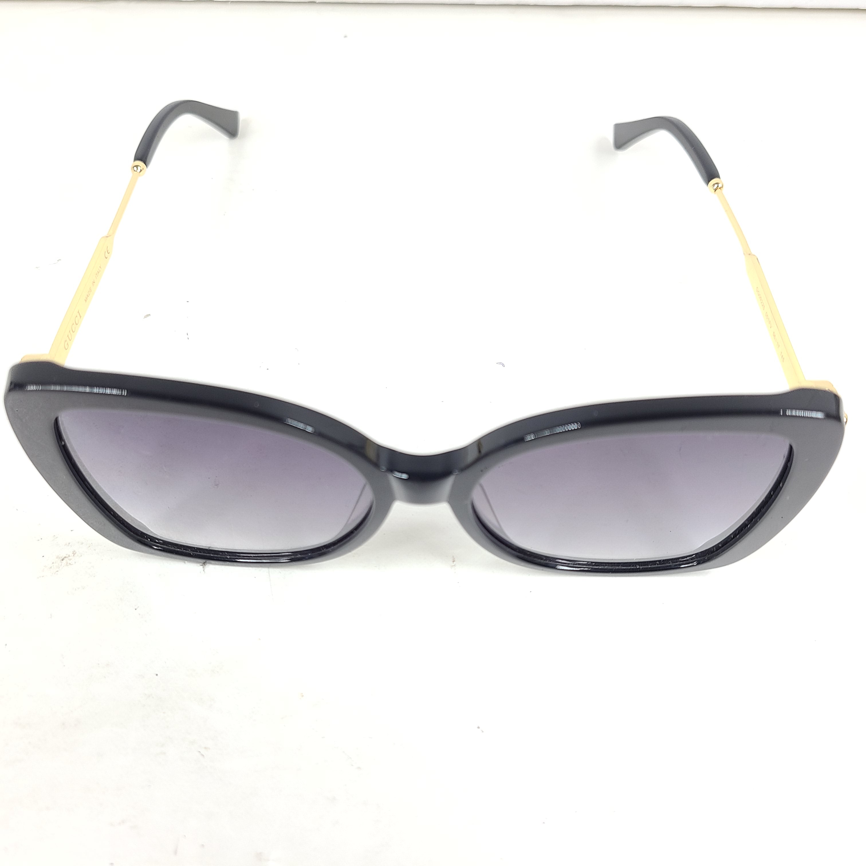 A stylish pair of Gucci women's sunglasses in black and gold gradient.