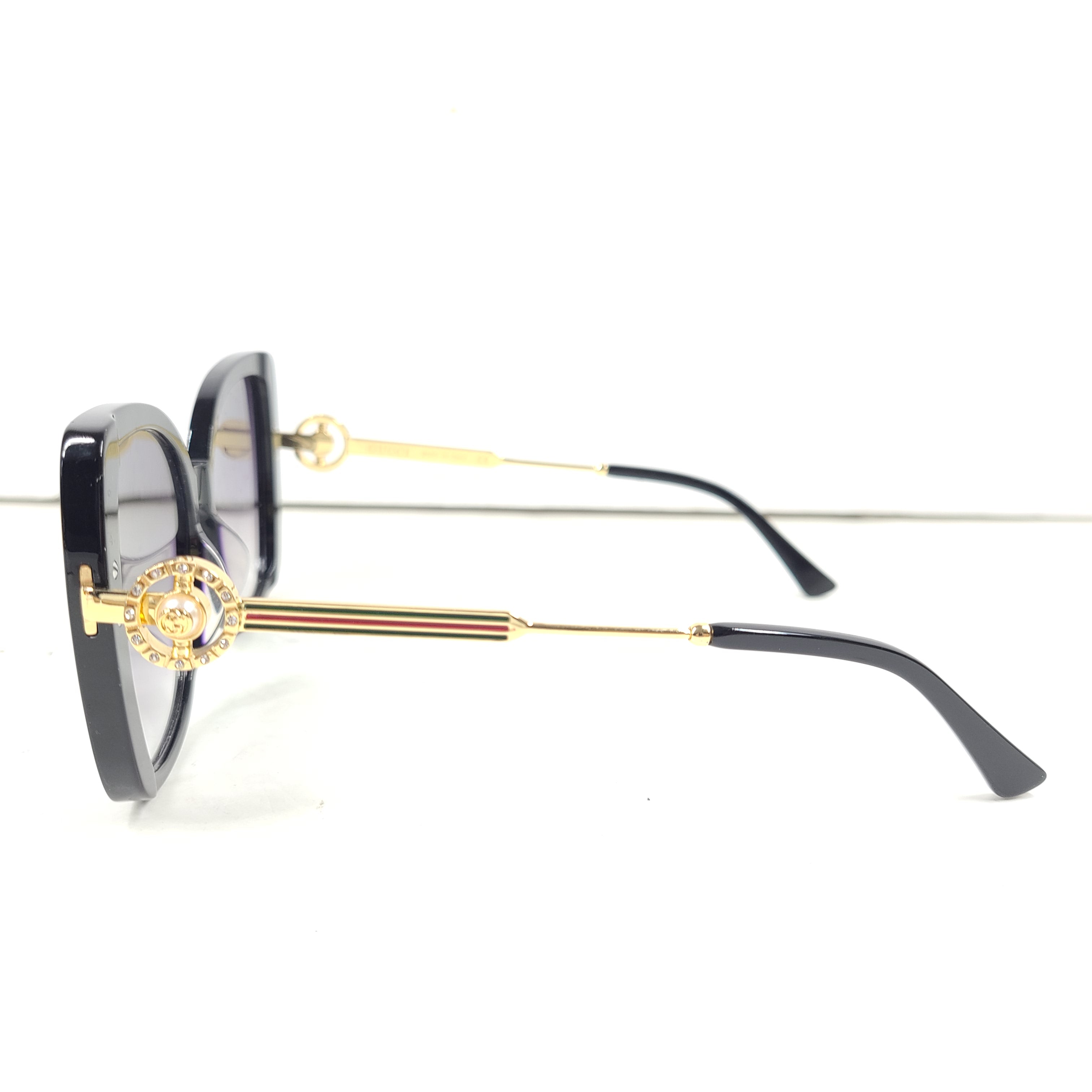 A stylish pair of Gucci women's sunglasses in black and gold gradient.