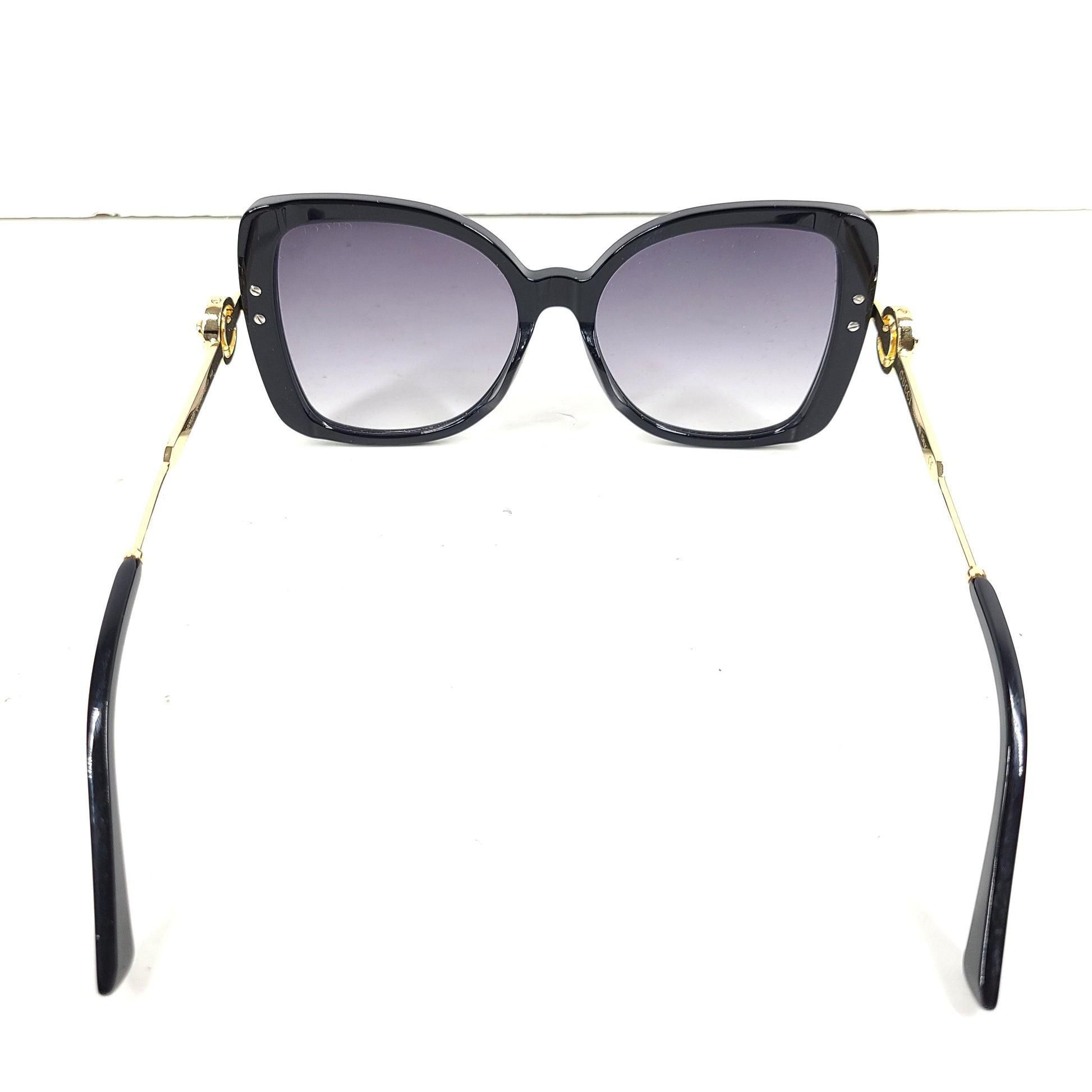 A stylish pair of Gucci women's sunglasses in black and gold gradient.