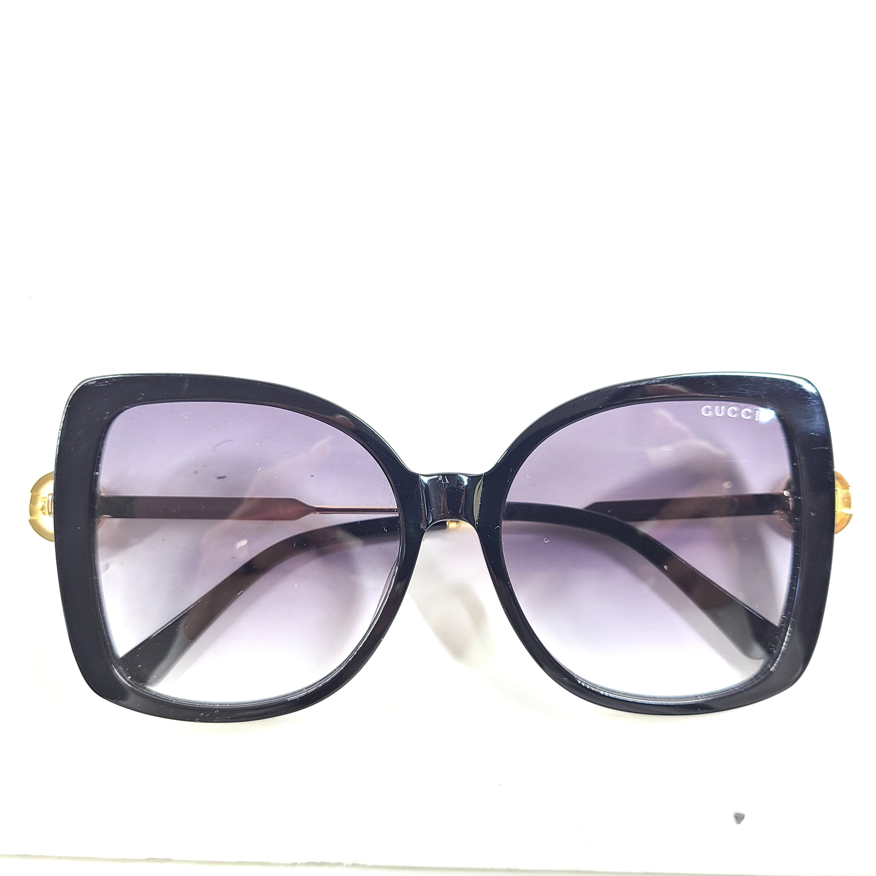 A stylish pair of Gucci women's sunglasses in black and gold gradient.