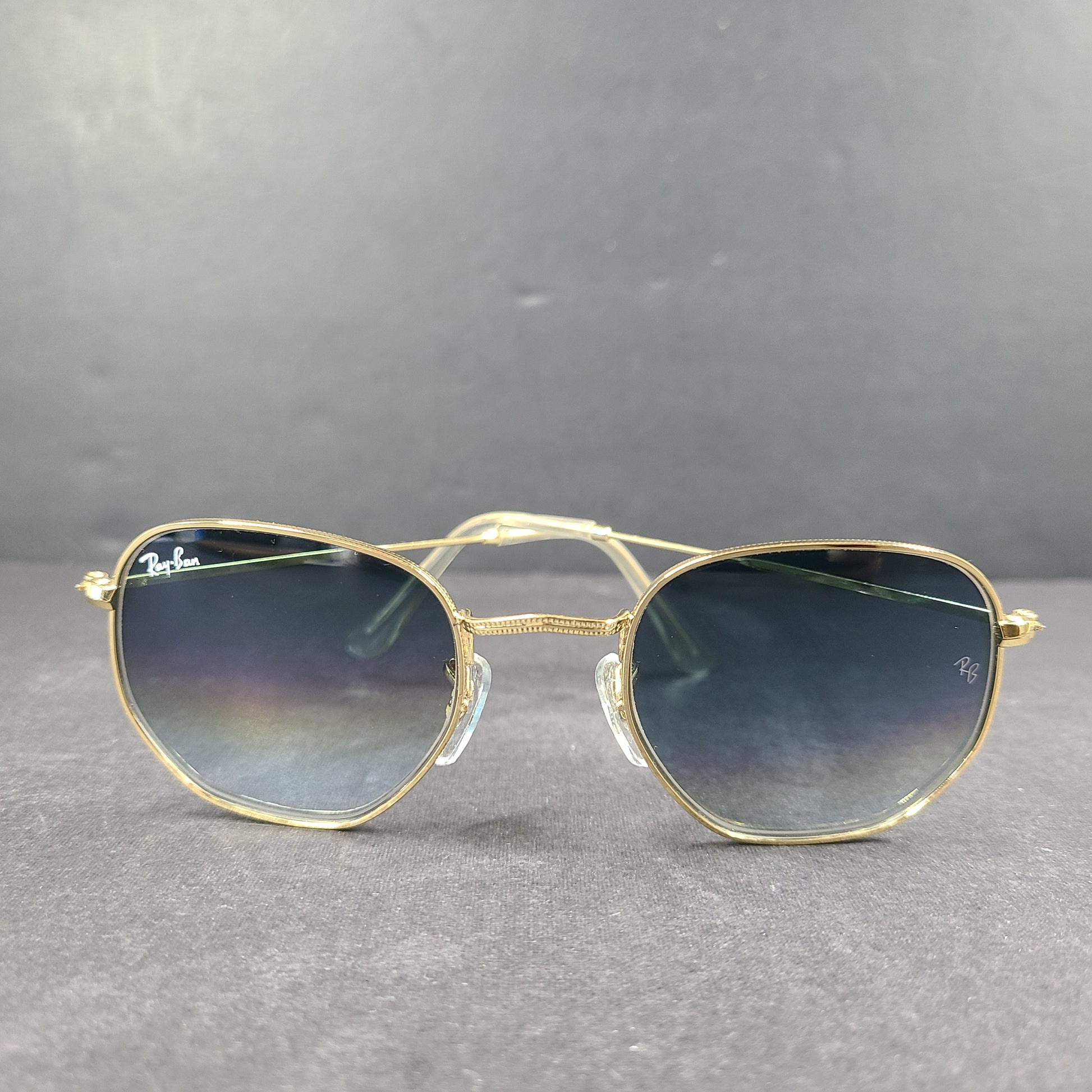 Fashionable Ray-Ban RB3548 Hexagonal Sunglasses with gold frames and blue lenses.