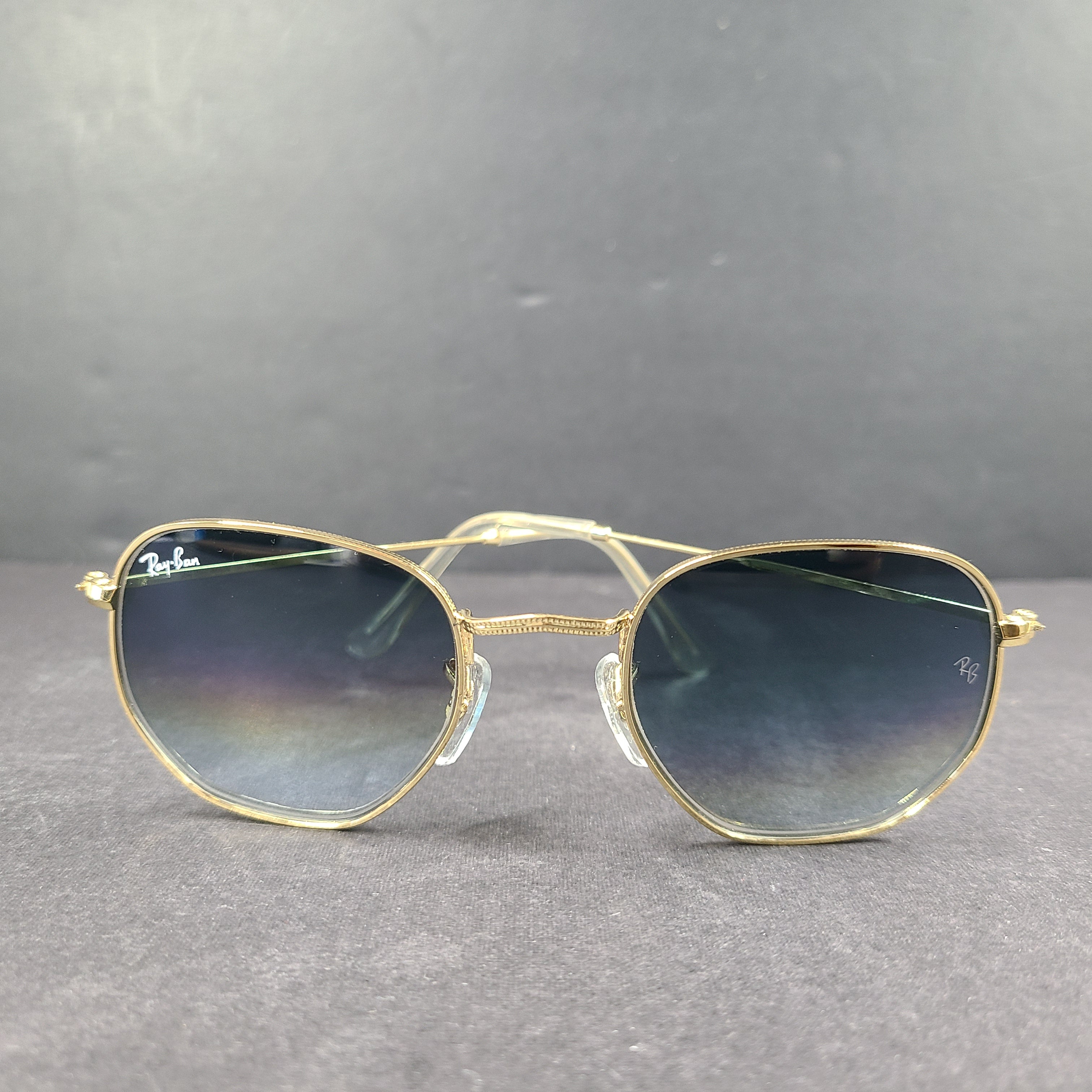 Fashionable Ray-Ban RB3548 Hexagonal Sunglasses with gold frames and blue lenses.