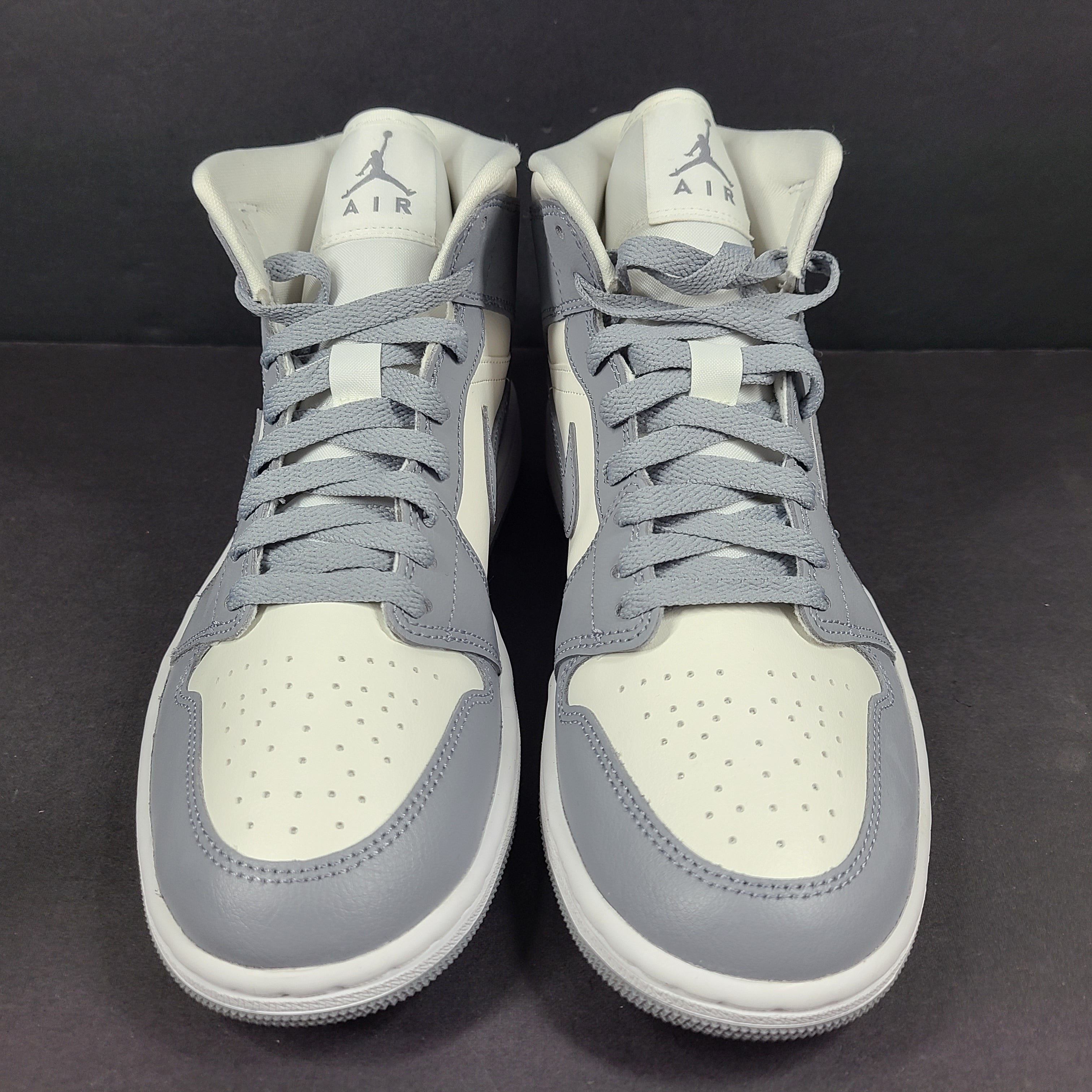 Nike Air Jordan 1 Mid in gray and white with a mid-top profile and classic Swoosh detailing for versatile streetwear styling.