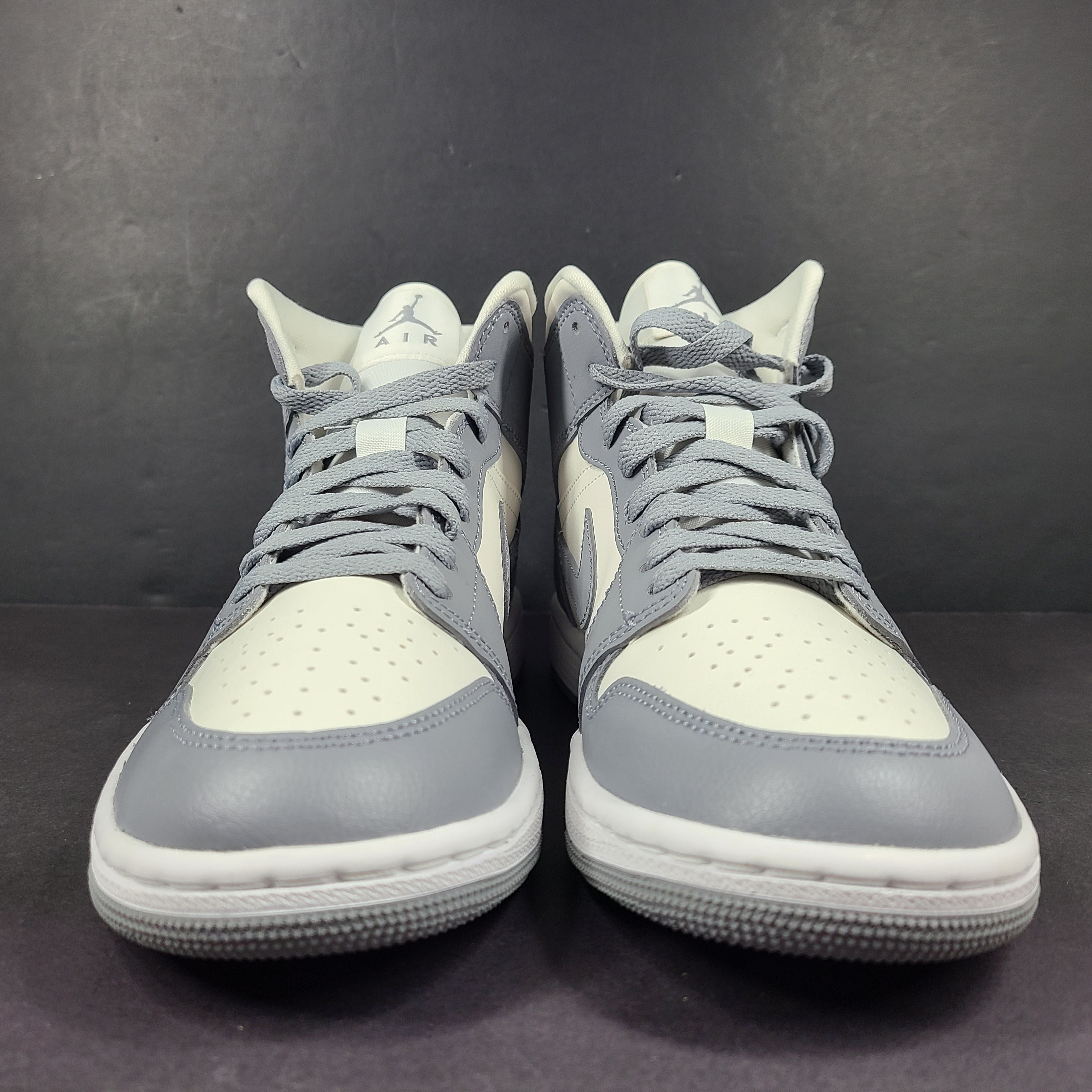 Nike Air Jordan 1 Mid in gray and white with a mid-top profile and classic Swoosh detailing for versatile streetwear styling.
