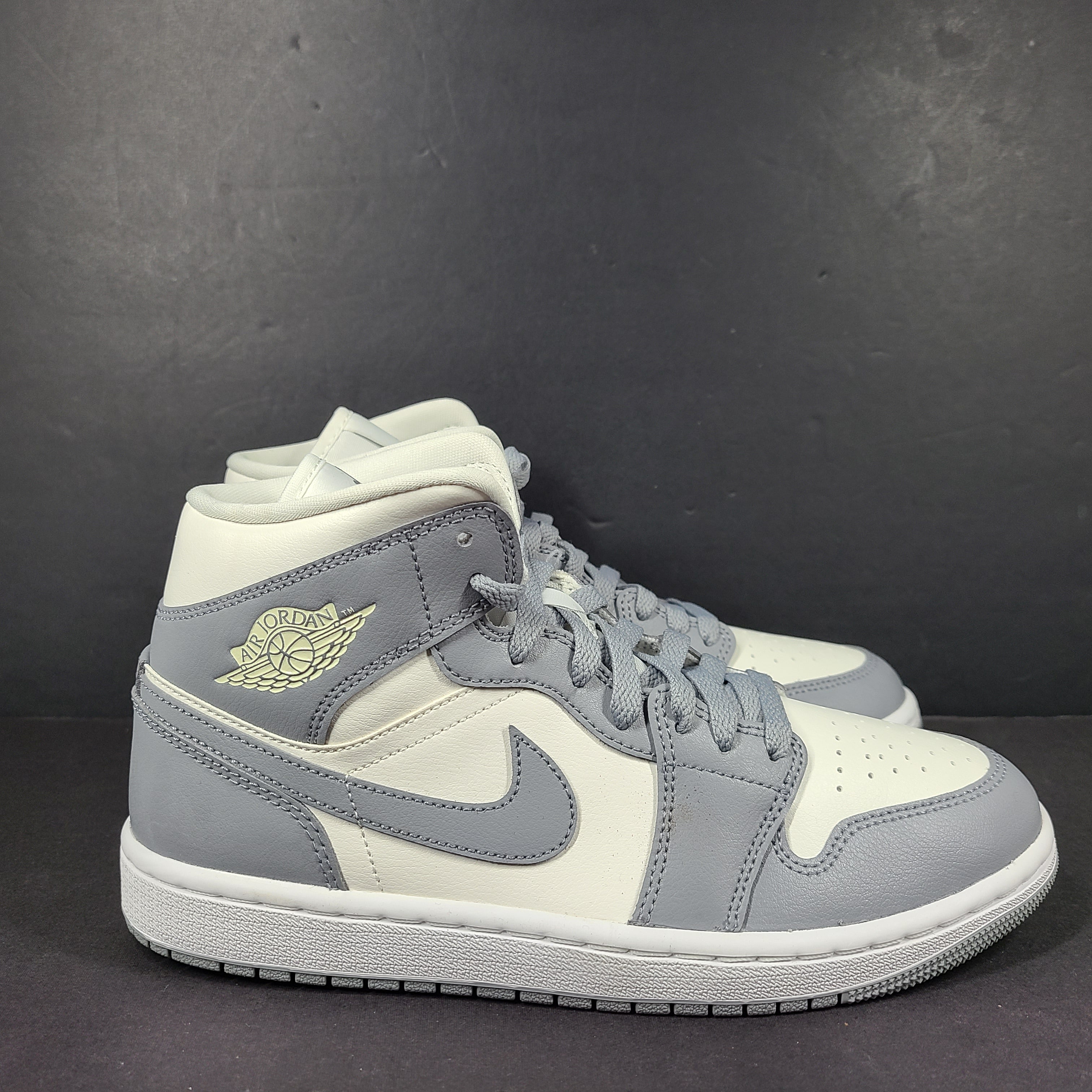 Nike Air Jordan 1 Mid in gray and white with a mid-top profile and classic Swoosh detailing for versatile streetwear styling.