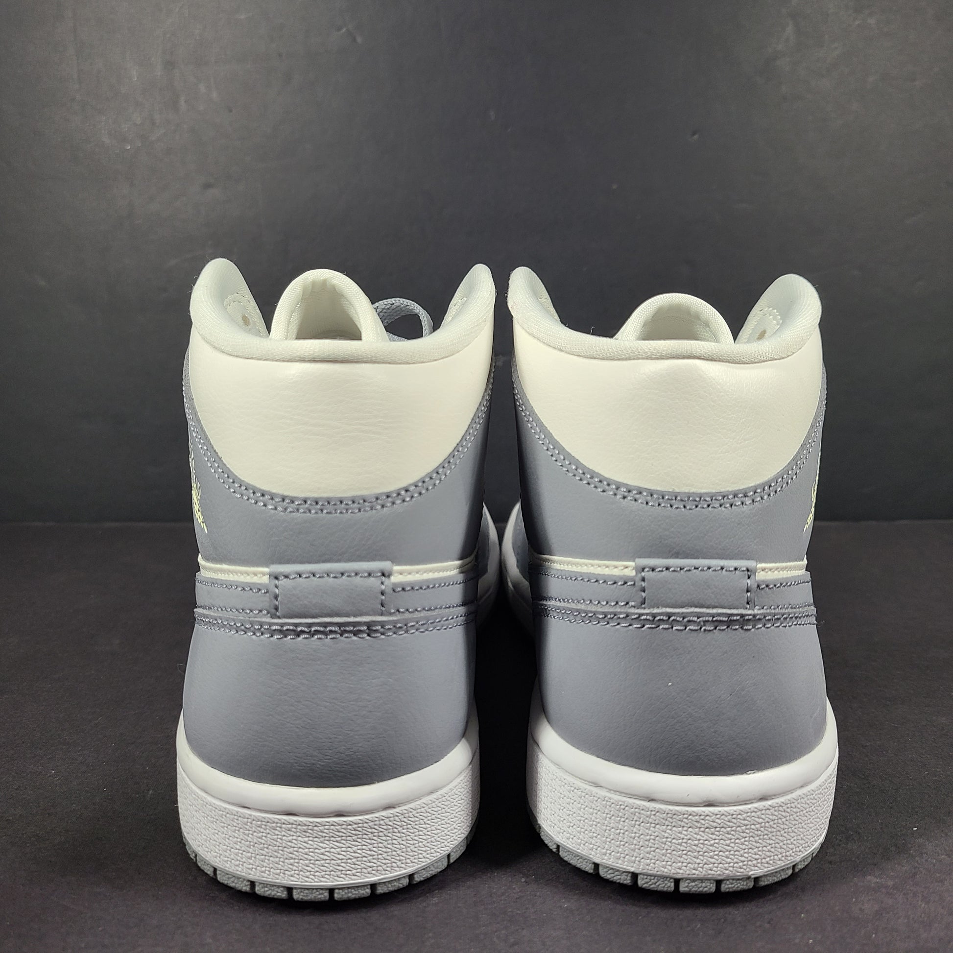 Nike Air Jordan 1 Mid in gray and white with a mid-top profile and classic Swoosh detailing for versatile streetwear styling.