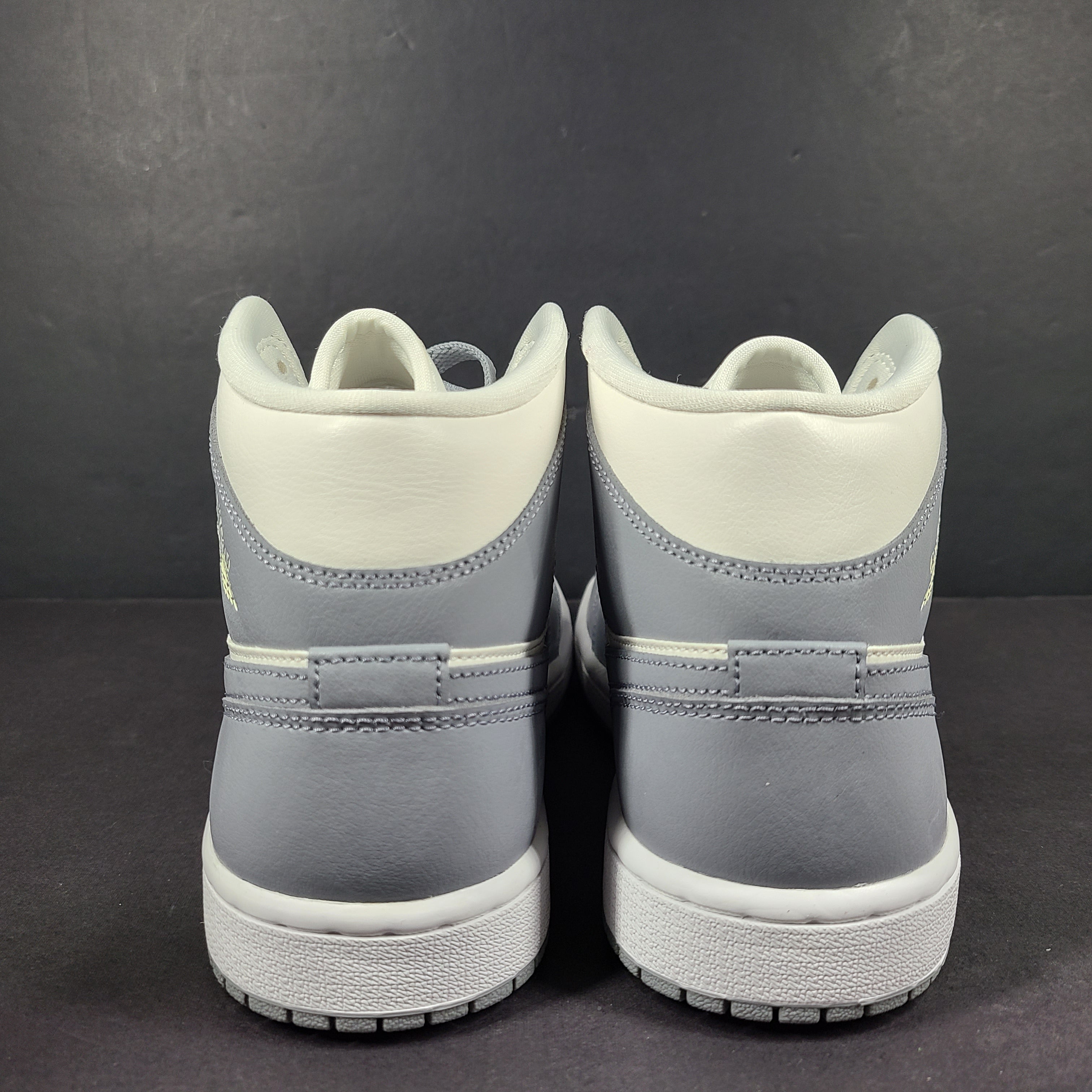 Nike Air Jordan 1 Mid in gray and white with a mid-top profile and classic Swoosh detailing for versatile streetwear styling.