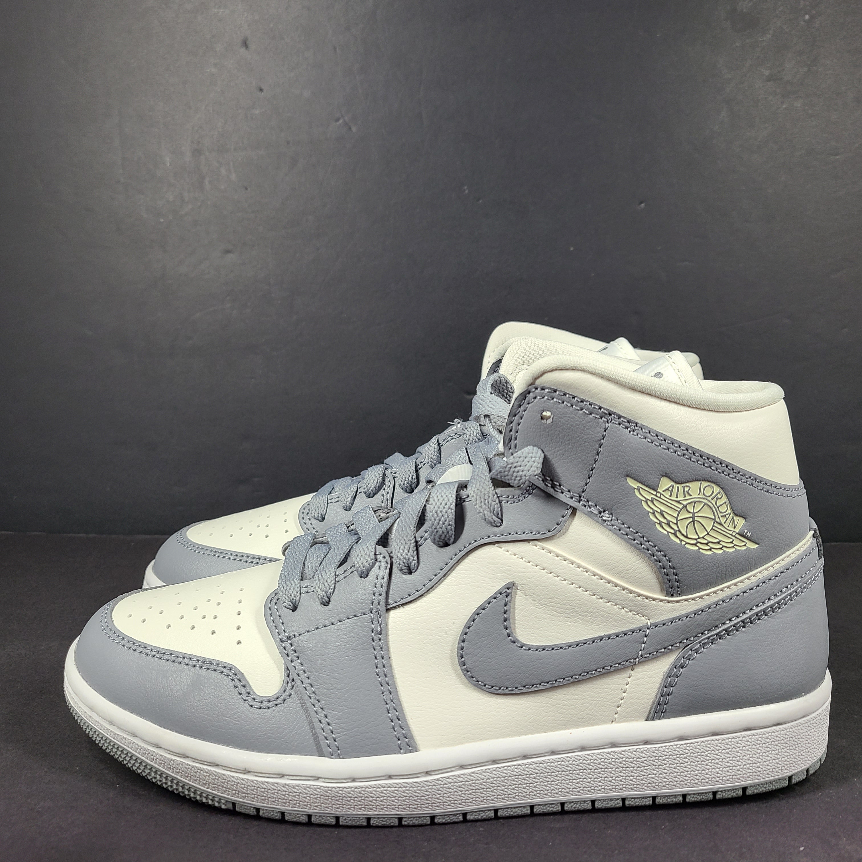 Nike Air Jordan 1 Mid in gray and white with a mid-top profile and classic Swoosh detailing for versatile streetwear styling.