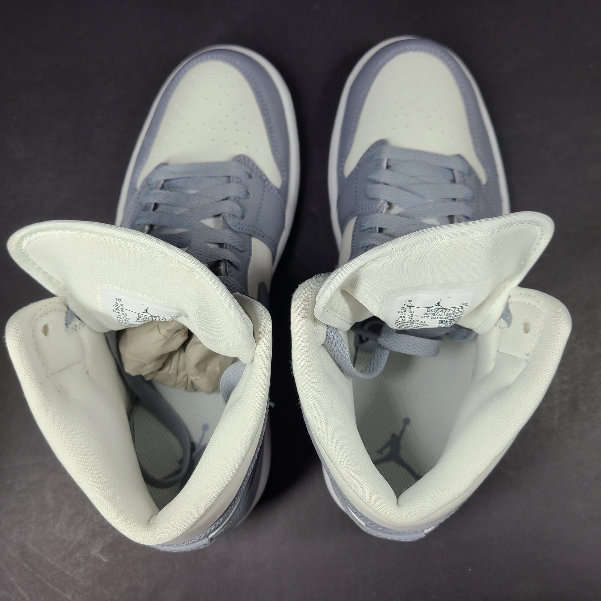 Nike Air Jordan 1 Mid in gray and white with a mid-top profile and classic Swoosh detailing for versatile streetwear styling.